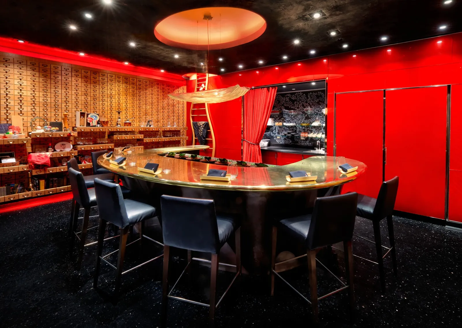 The room of é by José Andrés at The Cosmopolitan: 9 black stools round a curved gold counter, a wall of small wooden drawers and red lacquered walls with a red curtain to the kitchen
