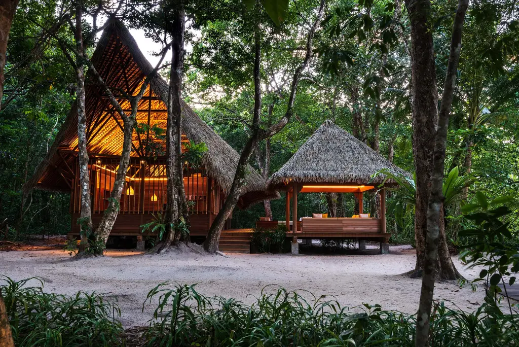 The Nature Centre’s timber and thatch pavilions under the trees at dusk