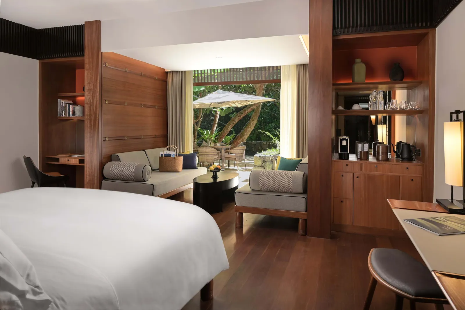 A Canopy Garden room, bed and sofa facing a glass door onto the patio and its umbrella