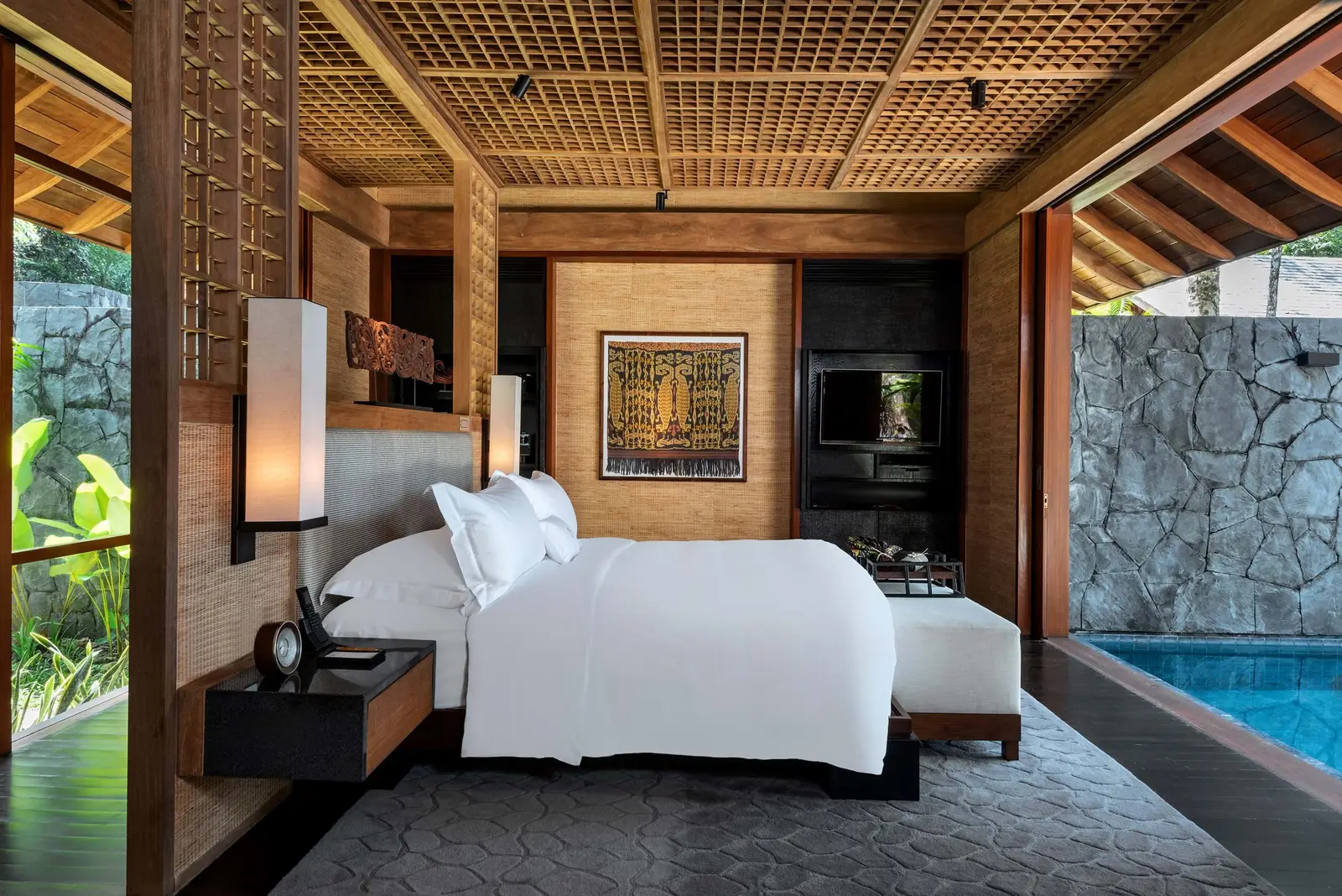 A One-Bedroom Beach Villa bedroom open on both sides, its private pool at the edge of the frame
