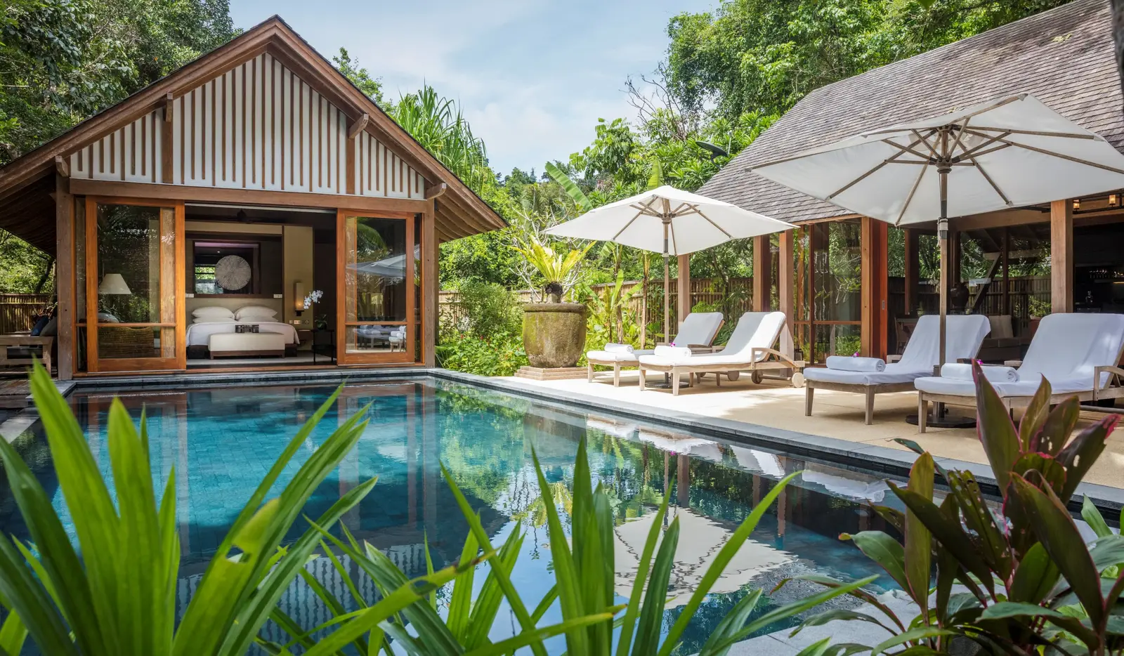 The Two-Bedroom Beach Villa’s pool, loungers and open pavilions among palms