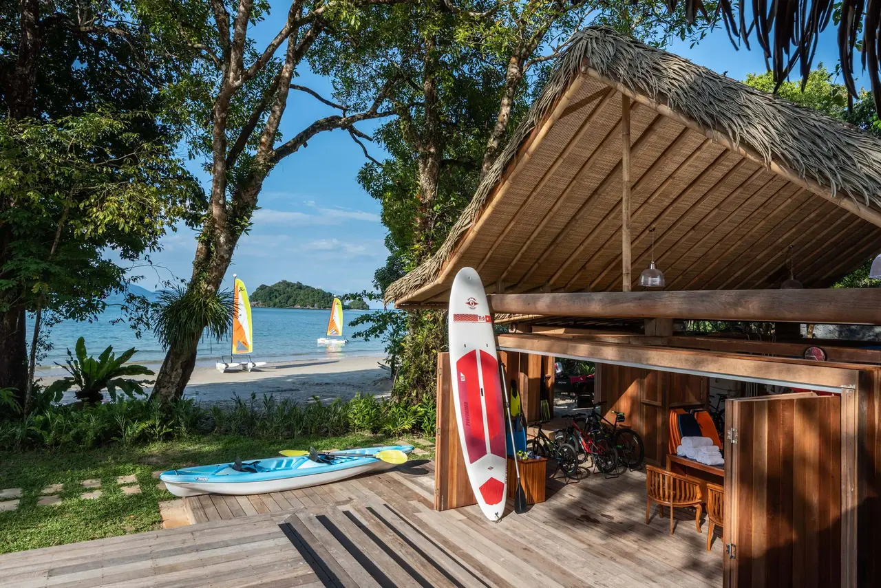 The watersports hut on the beach, boards and kayaks on the deck, catamarans on the bay