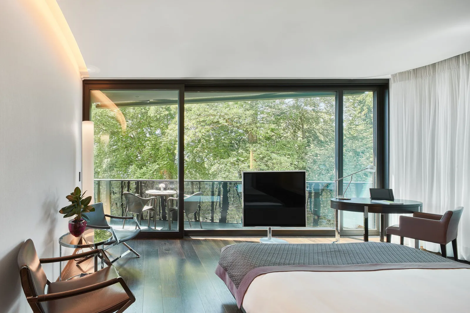 A Double Room Superior in the wing: the bed facing a glass wall onto the balcony and the trees