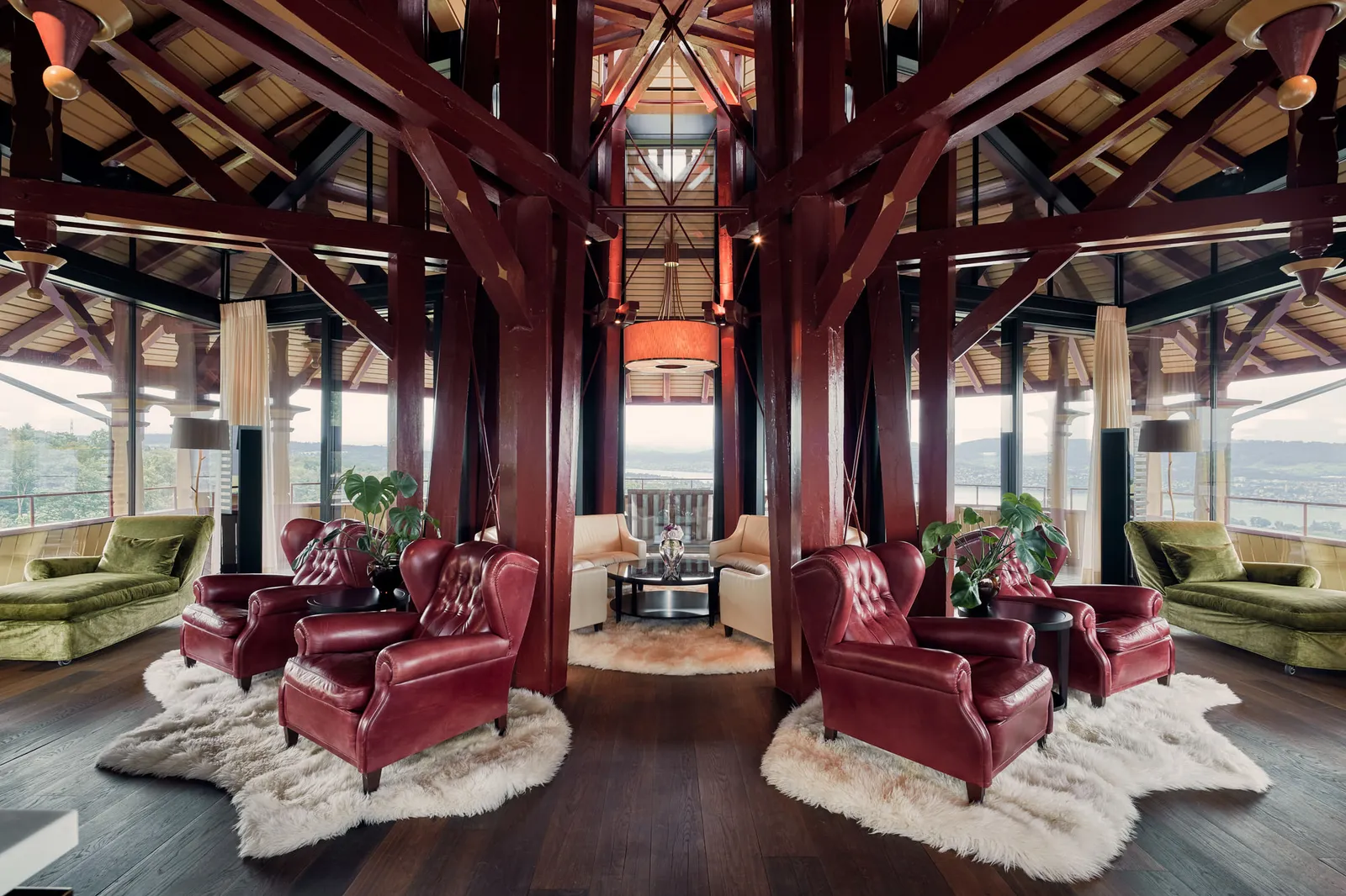 The living room of the Maestro Suite, one of the presidential suites, in the tower: red leather armchairs under the timber roof