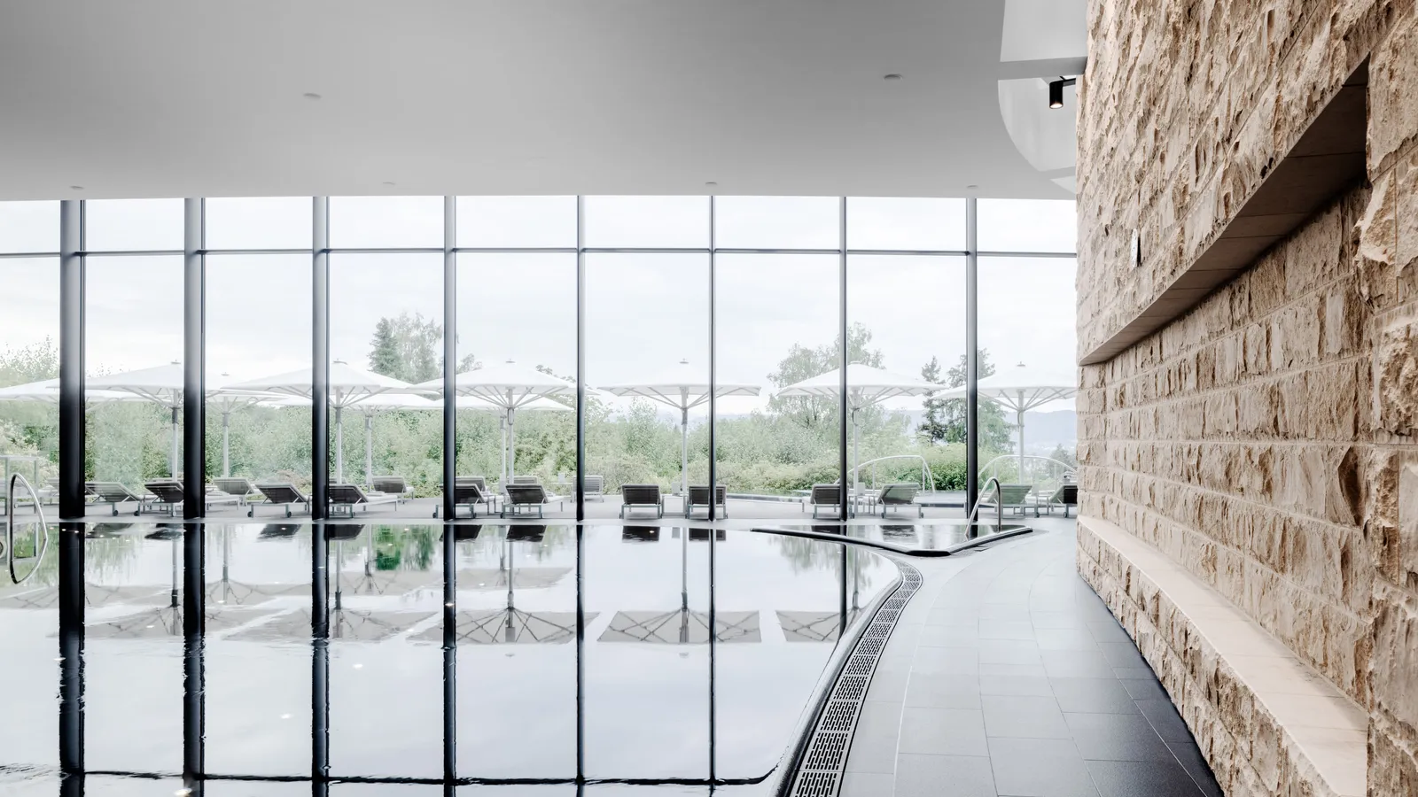 The indoor pool beside a rough stone wall, its glass front looking out to the parasols and loungers of the spa terrace