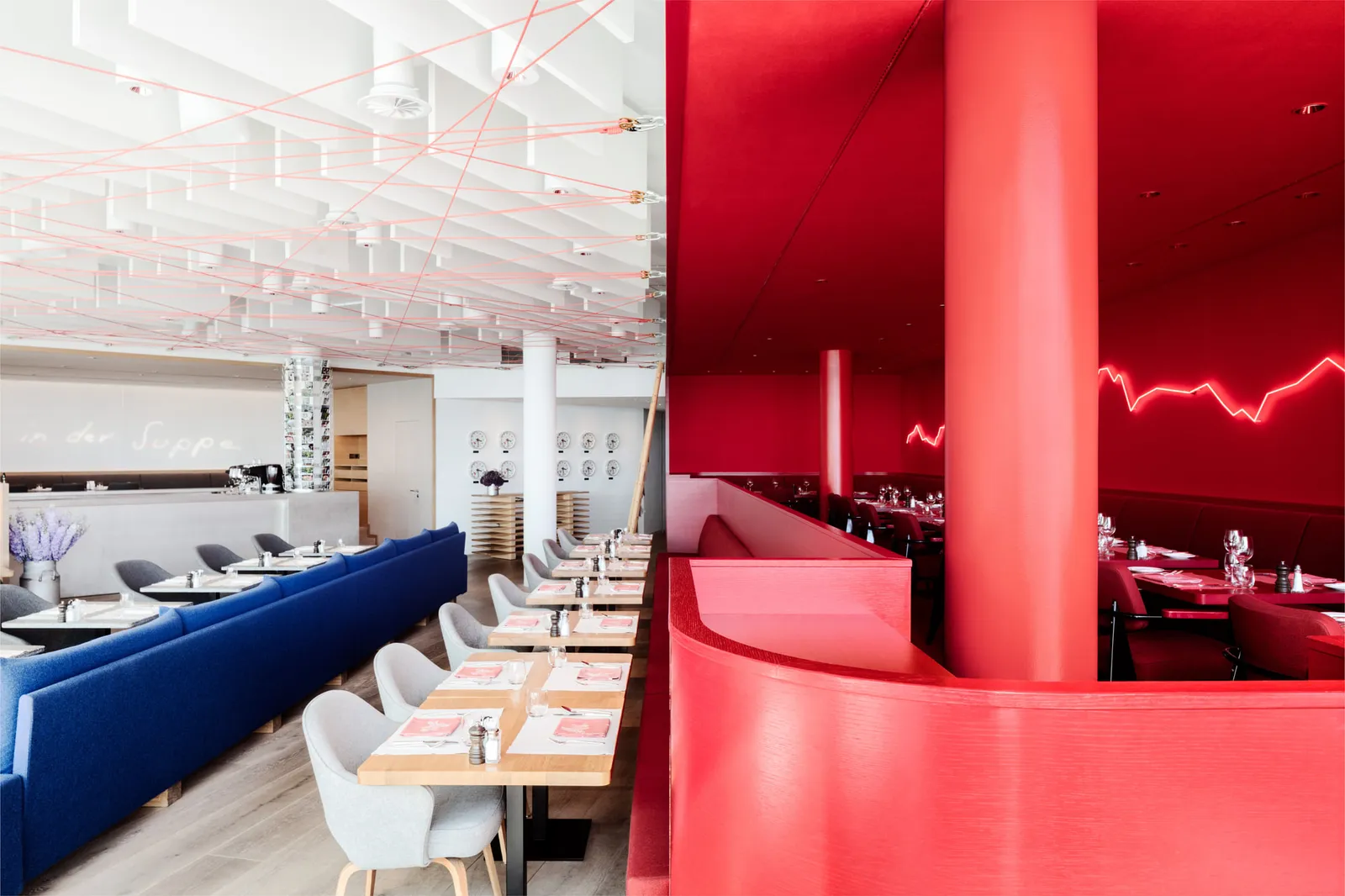 The Saltz restaurant: blue banquettes and wooden tables beside a red lacquered partition with a red neon line