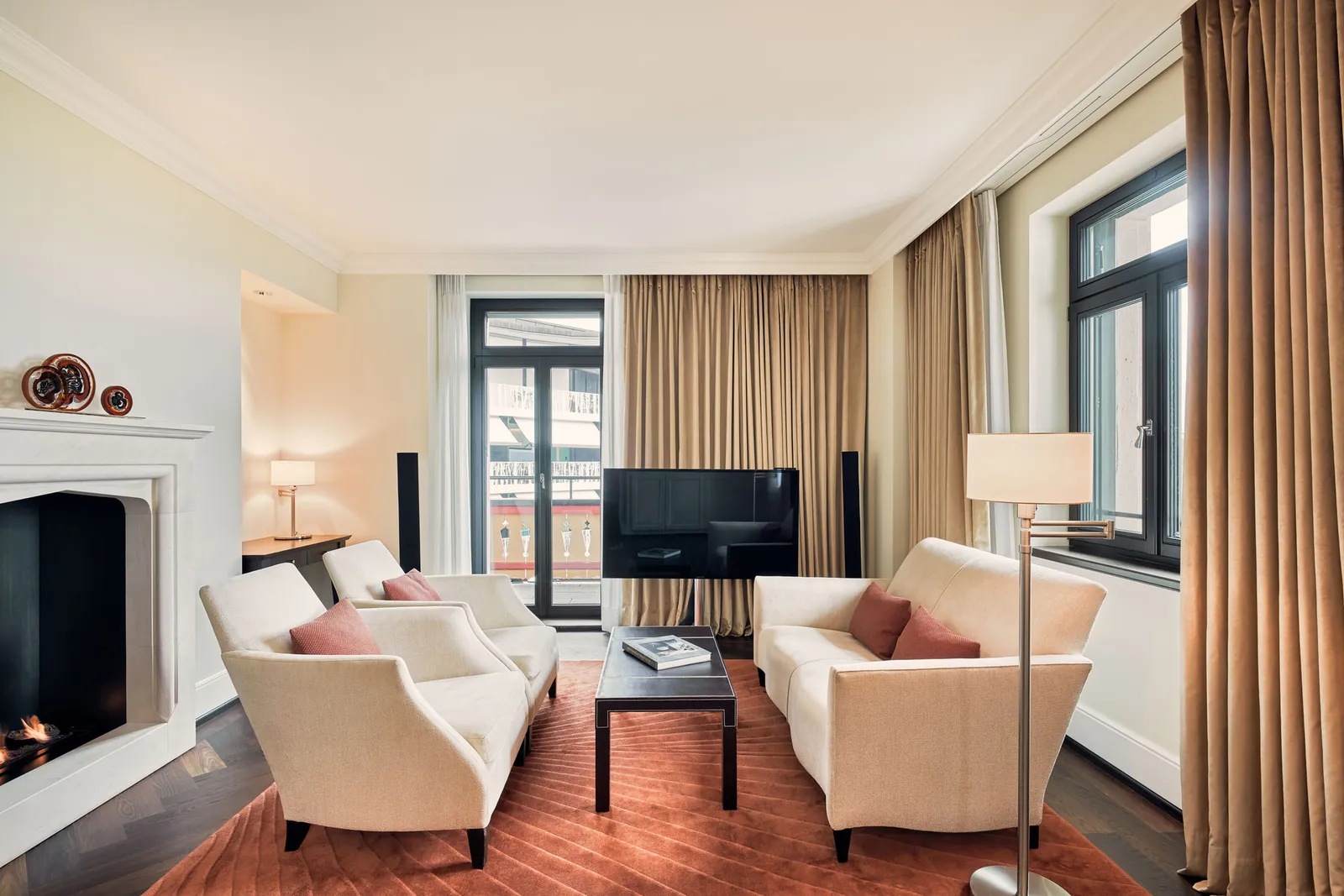 The living room of a Suite Superior: cream sofas, a fireplace and French windows onto the balcony