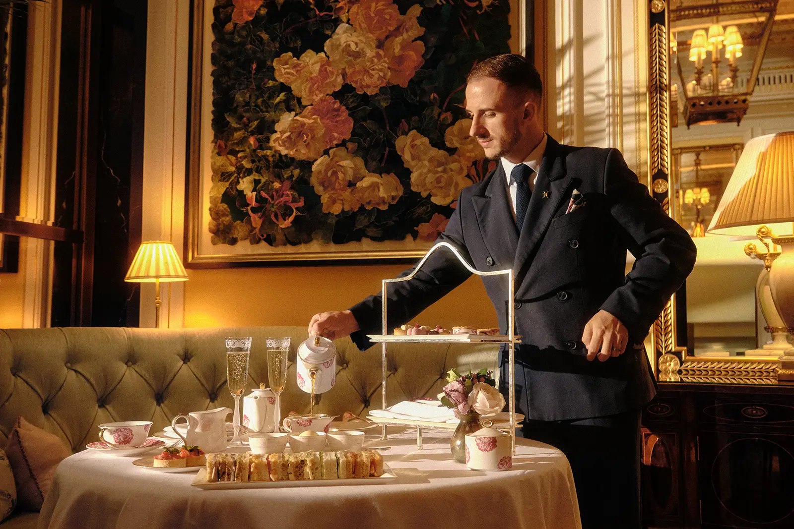 A waiter serves tea in The Promenade, the cake stand on the table