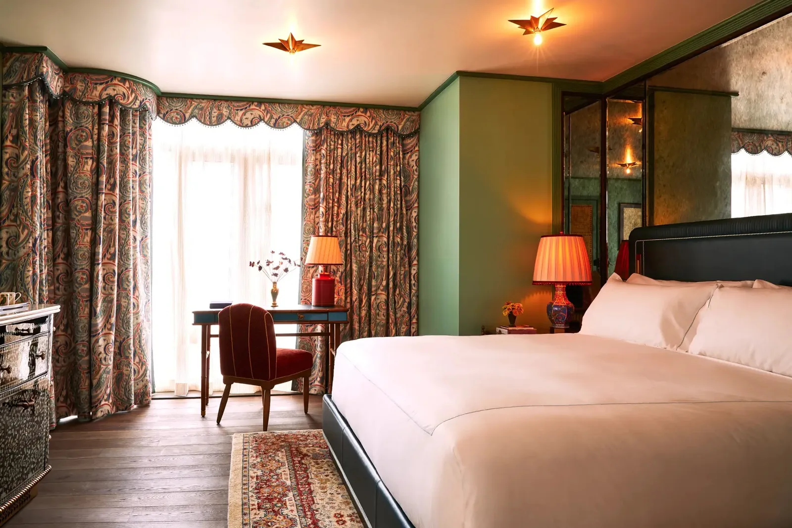 The Corner King with the bed, a writing desk and curtained windows