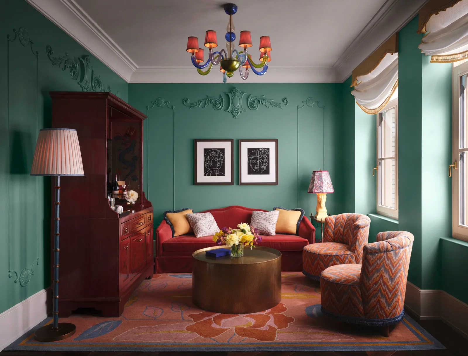 The Fifth Avenue Suite living room with a red sofa, a chandelier and green walls