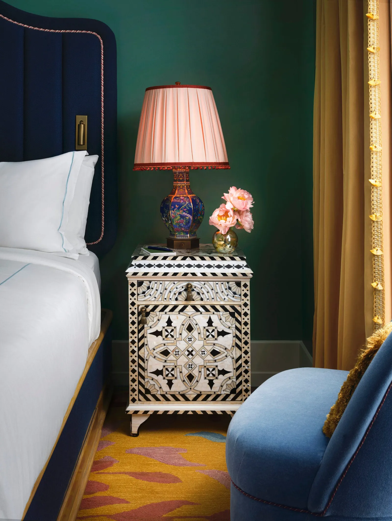 A corner of the Flâneur Penthouse bedroom: the white bed, an inlaid bedside table and a pink lamp