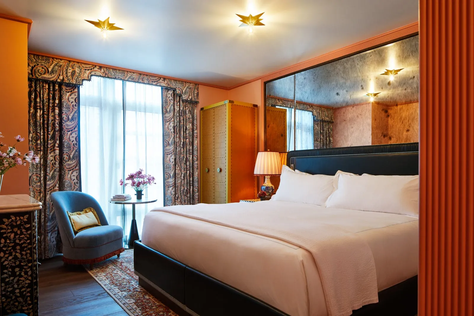 The Nomad King with its bed, a blue armchair and orange walls