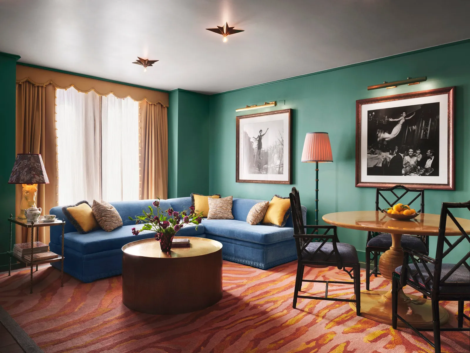 The One Bedroom Terrace Suite living room: a blue sofa, a round table and black-and-white prints