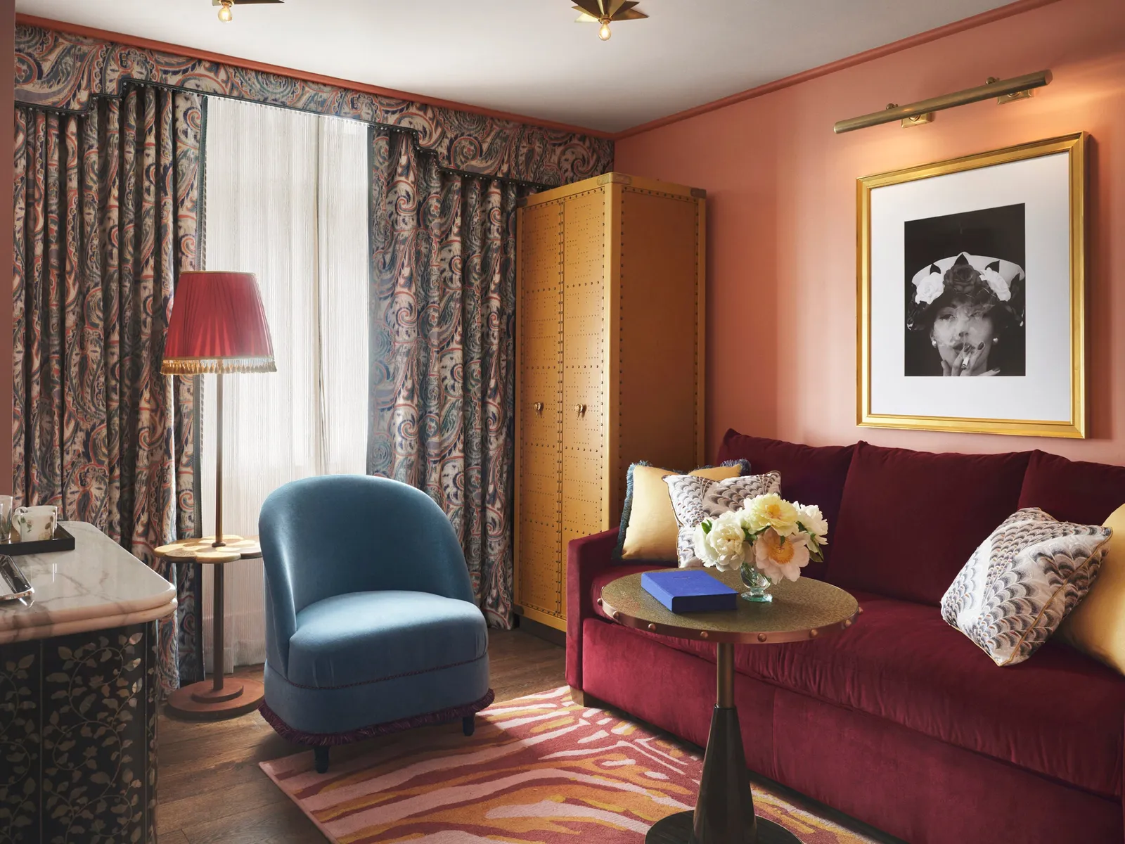 The Parlour Suite living room: a plum velvet sofa, a blue armchair, coral walls