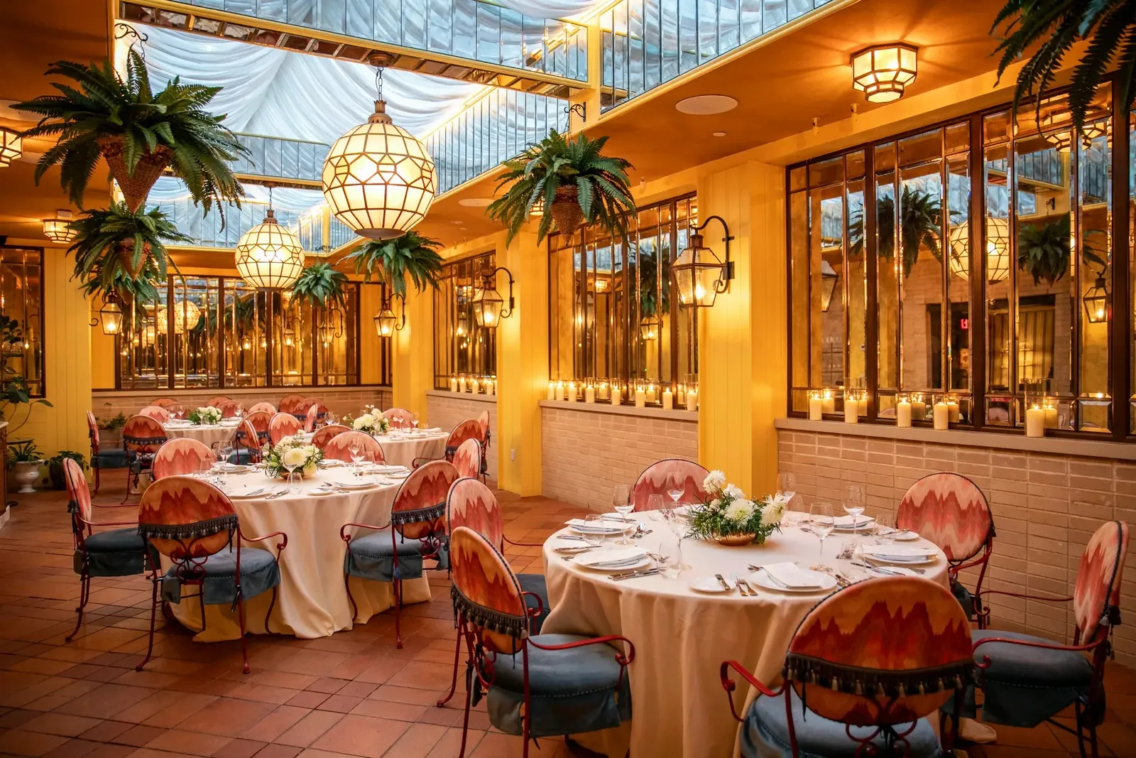 The Conservatory under its glass roof, round tables laid among the palms and lanterns