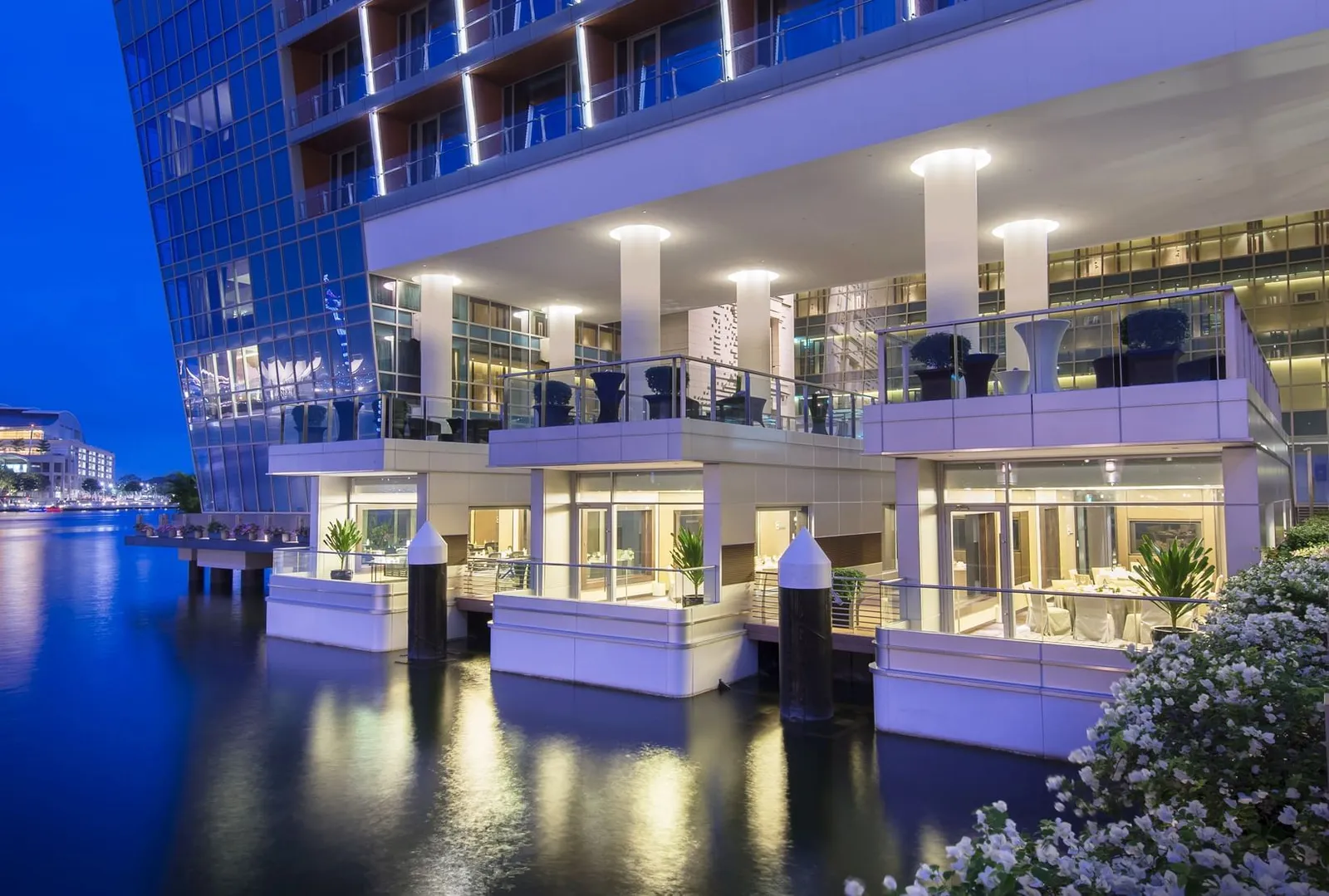 The glass-walled pods on the water at night, below the hotel’s lit façade.