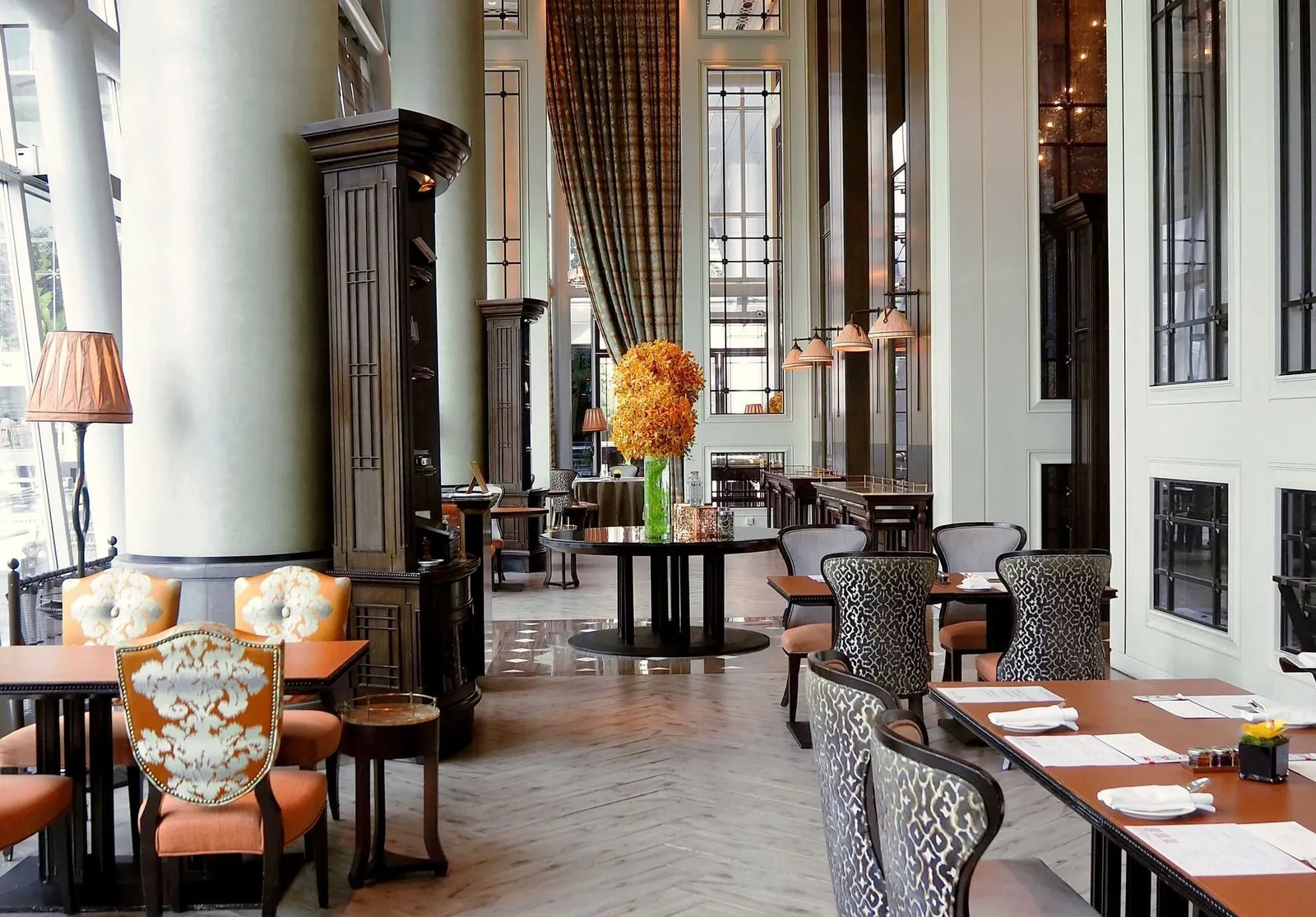 La Brasserie: tables and patterned armchairs between tall white columns and tartan curtains.