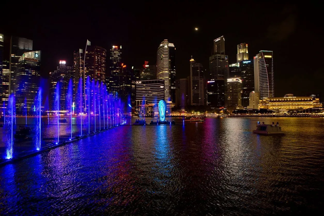 The light and water show on Marina Bay at night: fountains lit blue and violet, with the towers of the financial district behind.