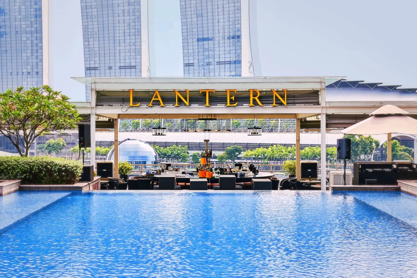 The rooftop pool by day, with Lantern’s sign beyond its edge and Marina Bay Sands across the bay.