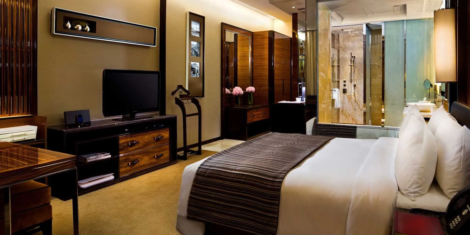 A Deluxe Room: the king bed, the desk and television to the left, the glass-walled bathroom at the back.