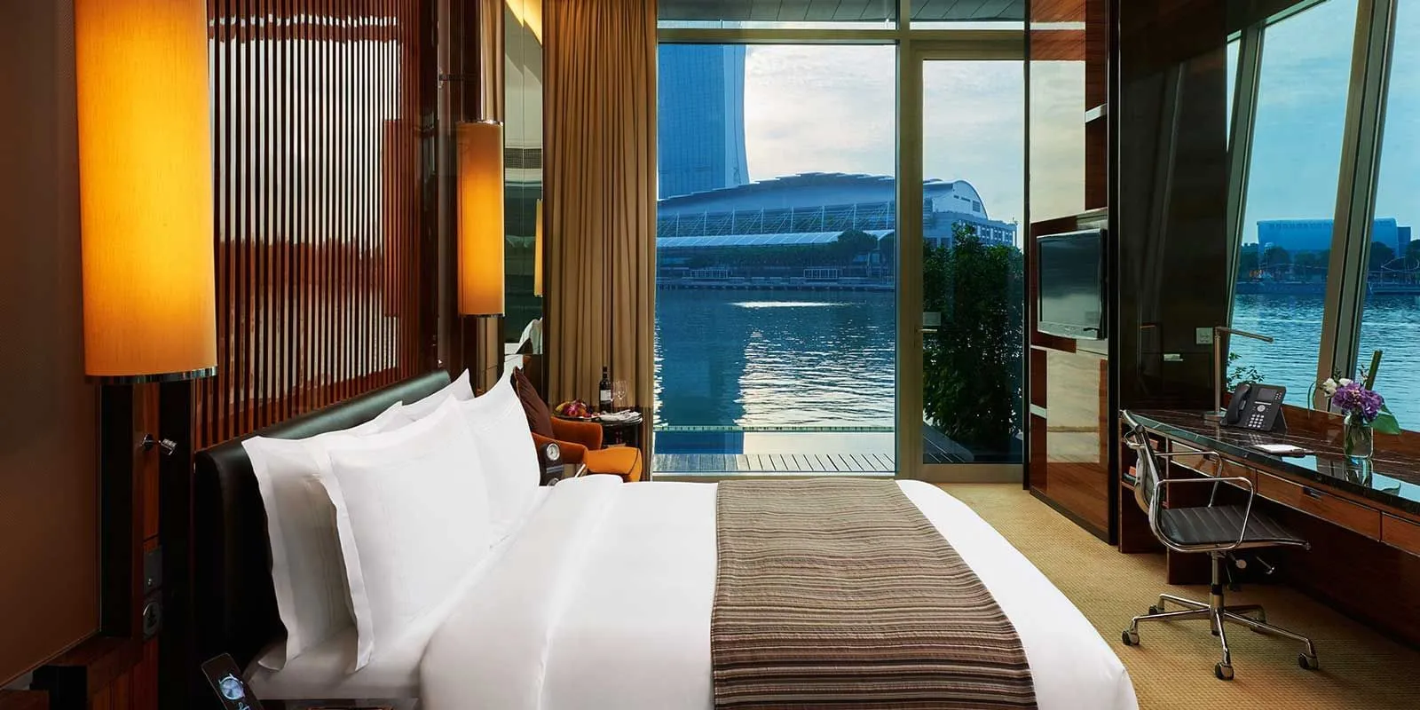 A Premier Bay View Room with Jacuzzi: the bed facing glass doors that open onto a deck level with the water.