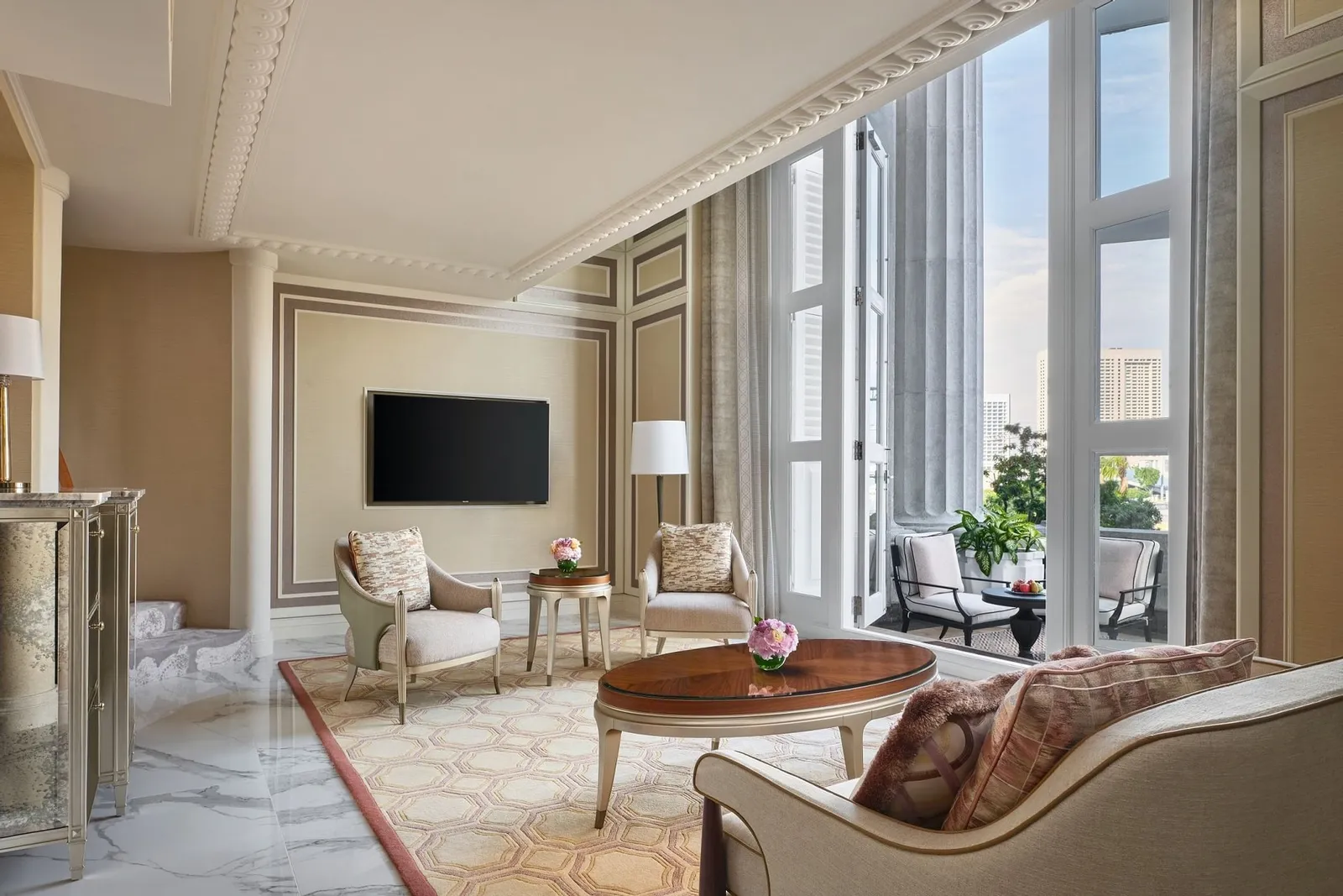 Il salotto di una Loft Suite: poltrone e un tavolo rotondo davanti a portefinestre a doppia altezza, con la scala a chiocciola a sinistra