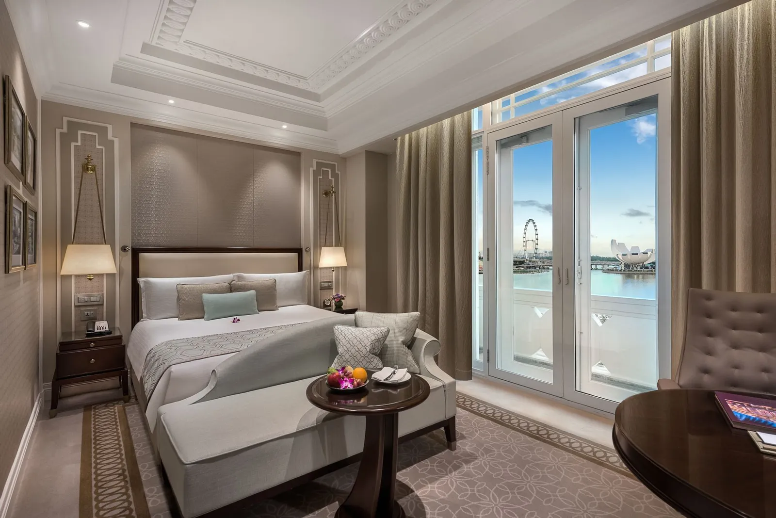 Una Marina Bay View Room: letto king davanti alle portefinestre aperte sul balcone, con la baia e il Singapore Flyer sullo sfondo