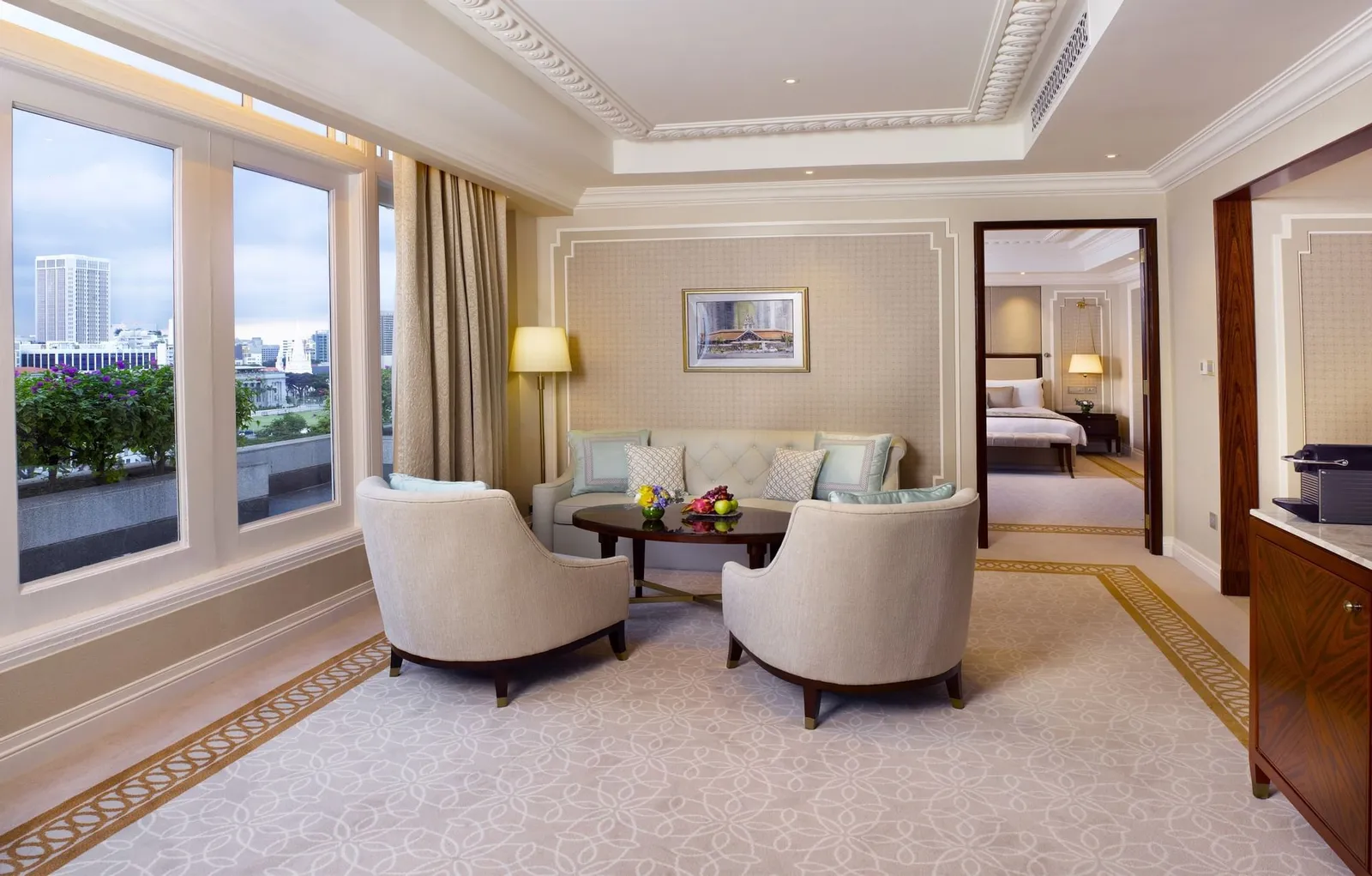 Il salotto di una Palladian Suite: poltrone color crema intorno a un tavolino, finestre sulla baia e una porta verso la camera