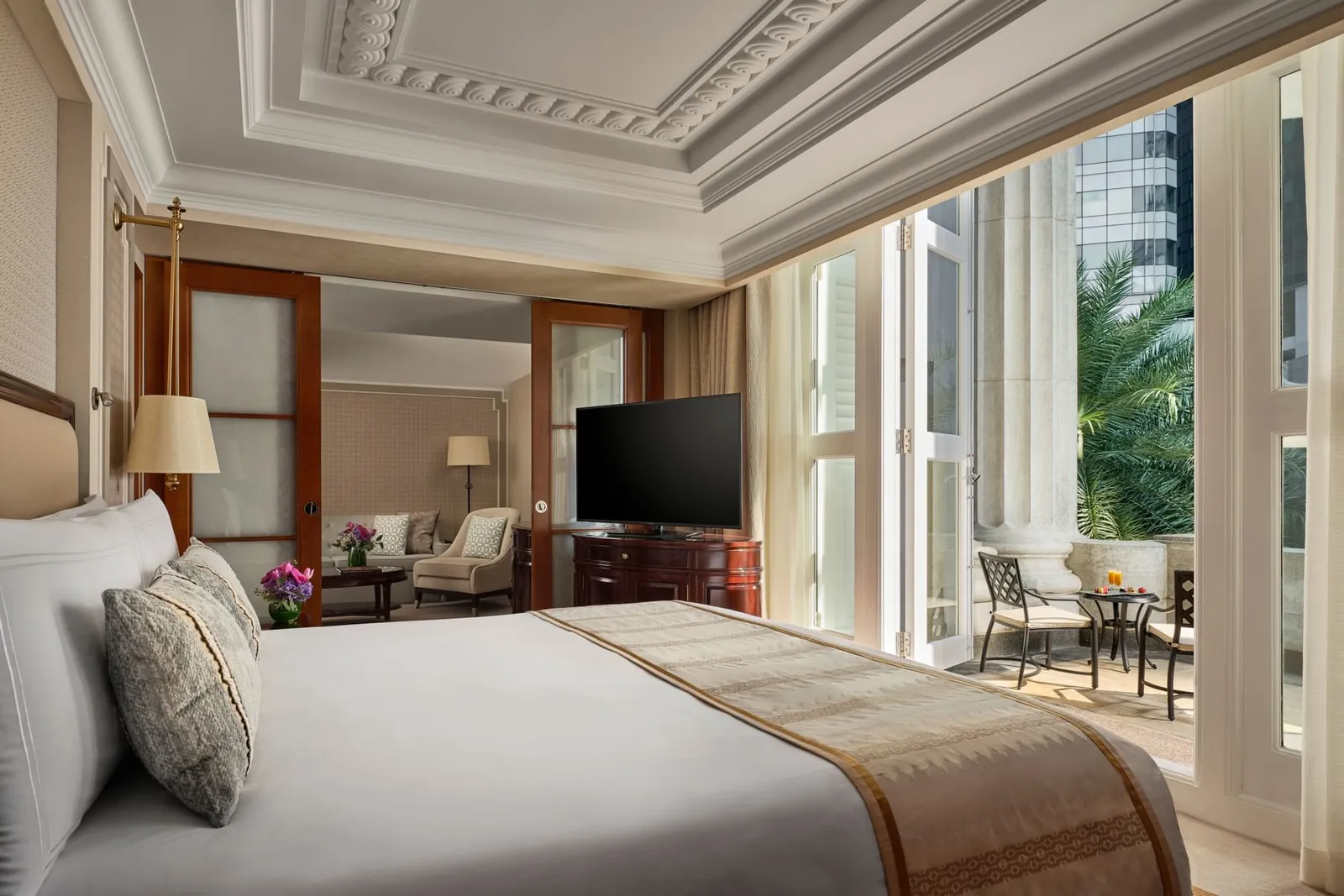 La camera da letto di una Premier Collyer Suite: letto con un runner a disegni, televisore e porte a vetri su un balcone con le sedie