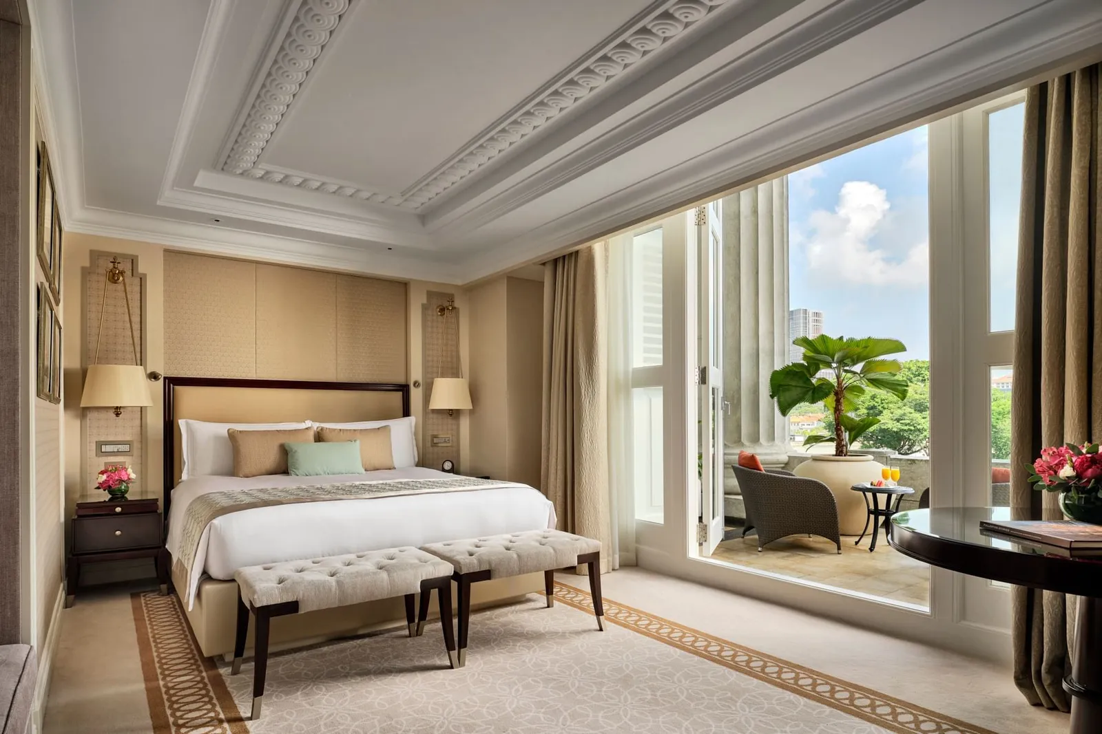 Una Quay Pool View Room: letto king con una panca ai piedi e la porta del balcone aperta, con le poltrone fuori