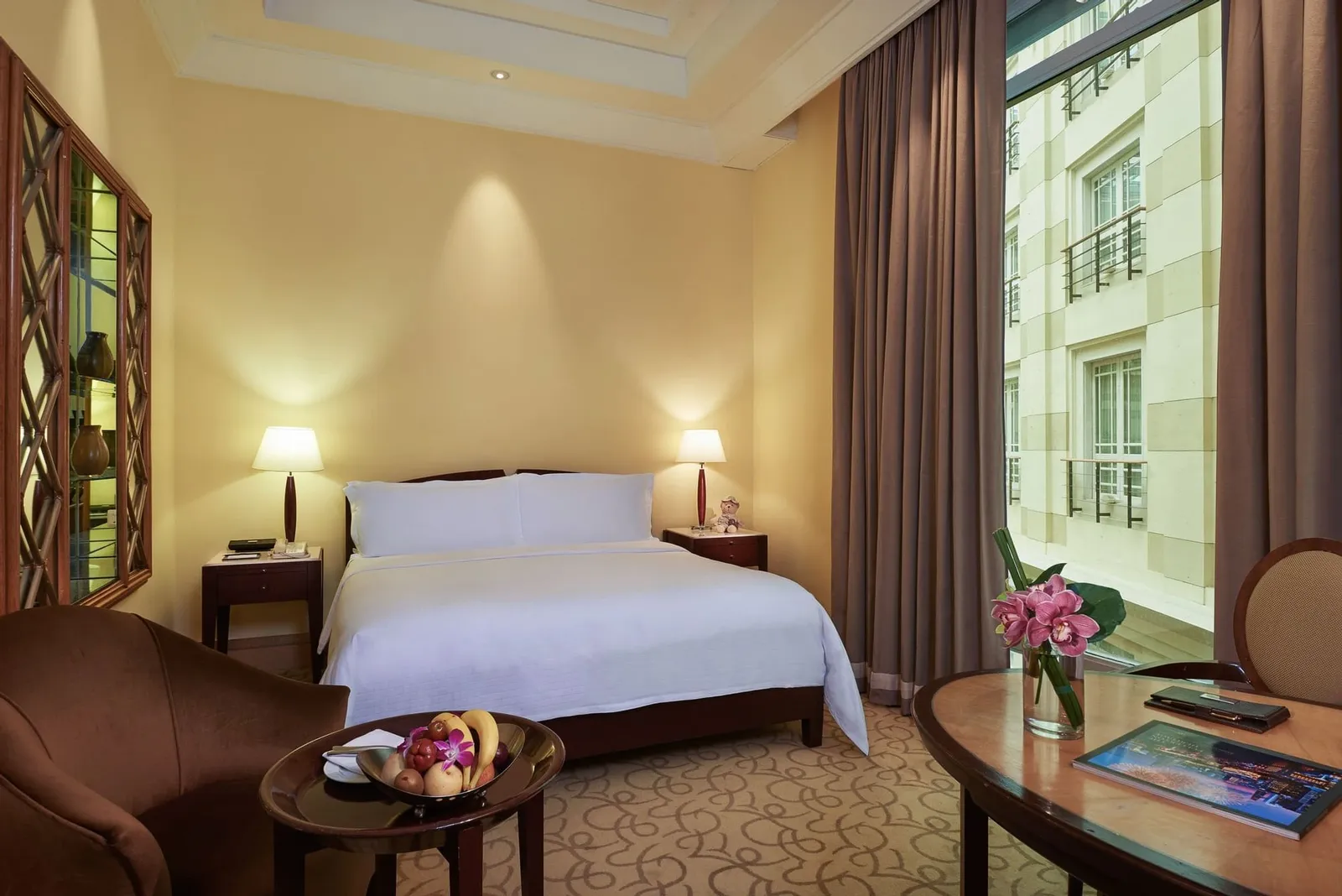 Una Straits Club Courtyard Room: letto bianco, mobili di legno scuro e una finestra con le persiane sulla facciata interna dell’atrio