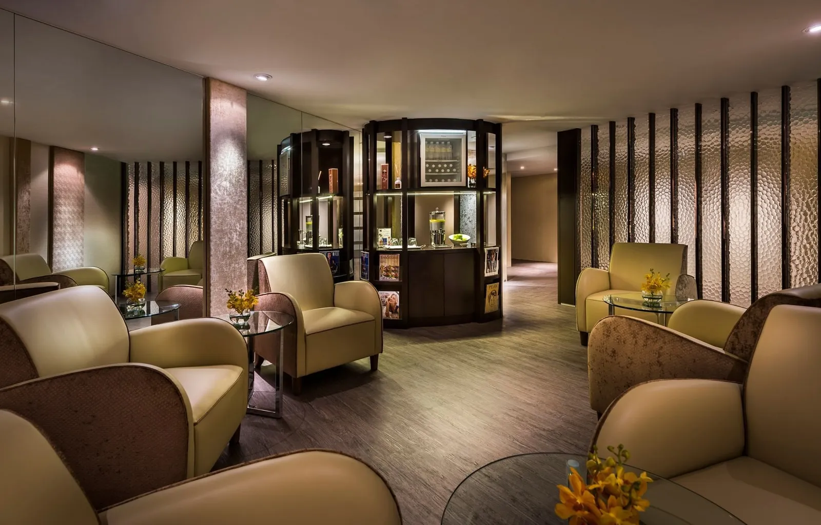 La sala relax della spa: poltrone di pelle color crema, scaffali di legno scuro e luce bassa
