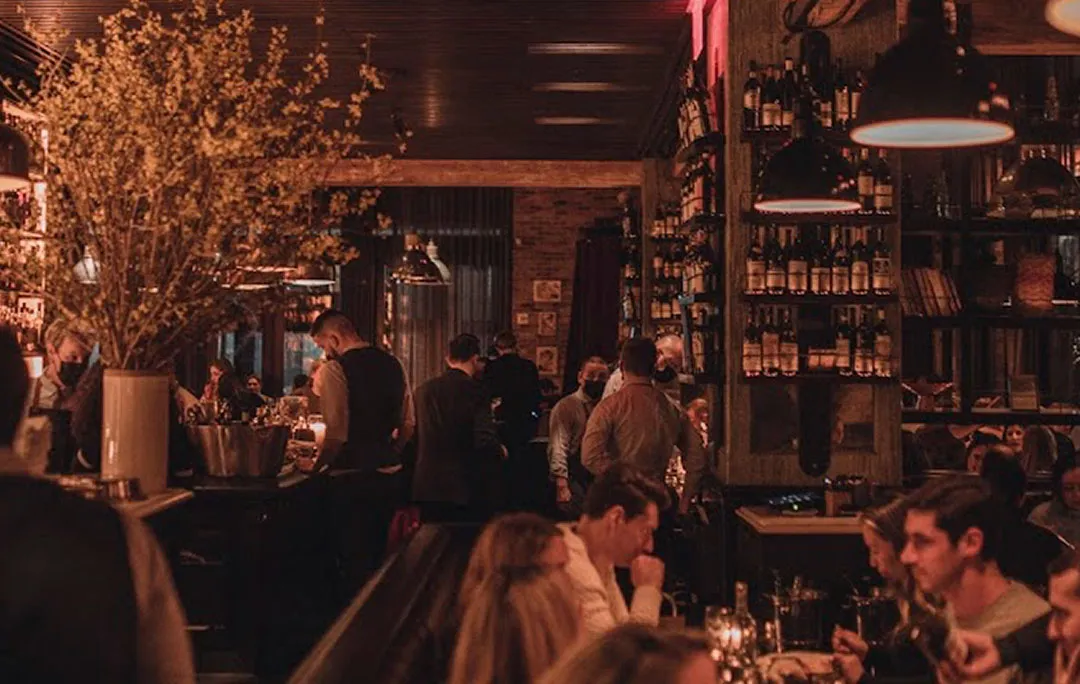 Locanda Verde’s busy dining room at night, the bar and the lamps