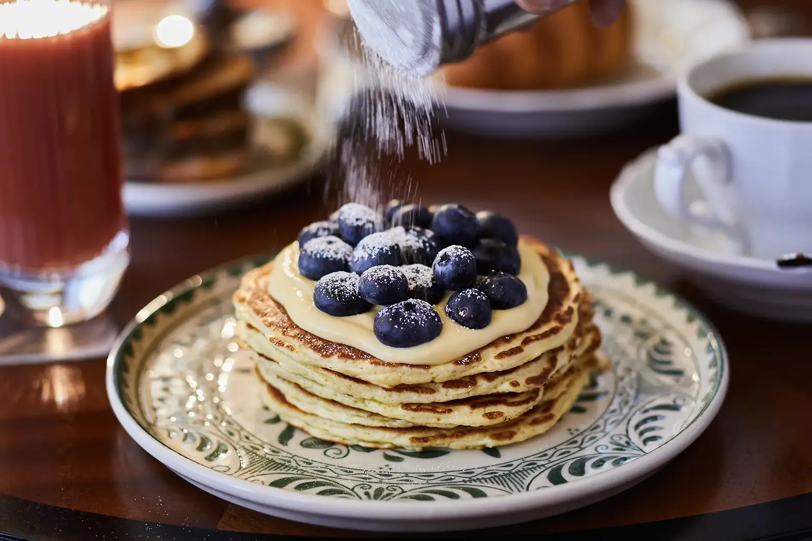 Lemon ricotta pancakes with blueberries, icing sugar falling