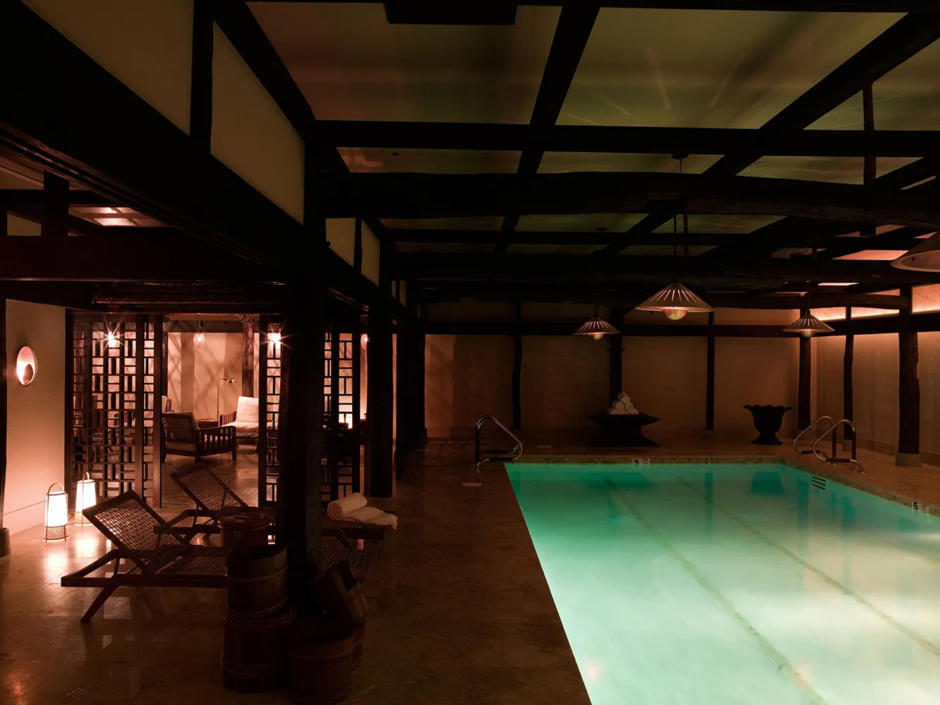 Shibui’s pool among dark beams and loungers, the lanterns lit