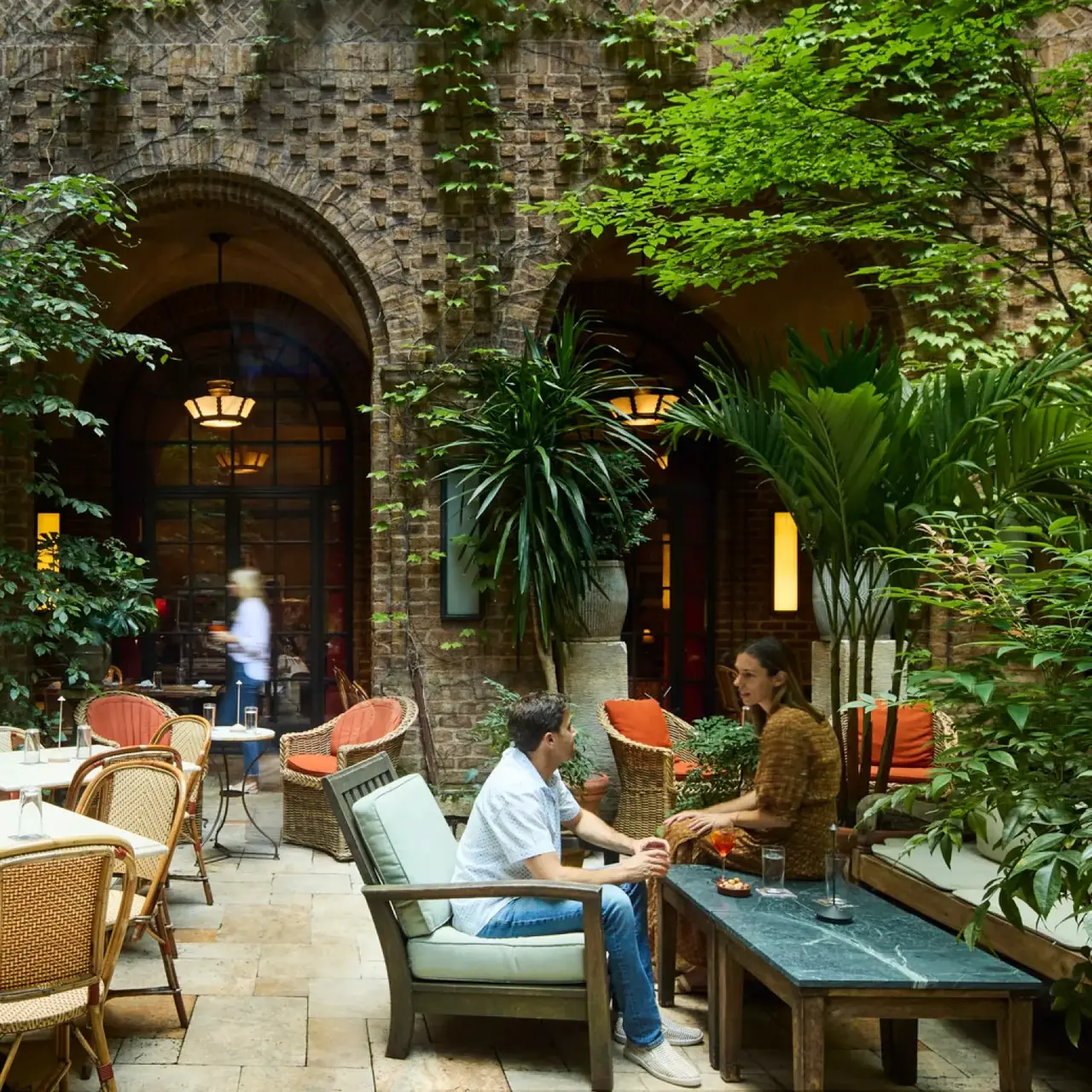 The Greenwich's inner courtyard, guests at the tables among plants and brick arches