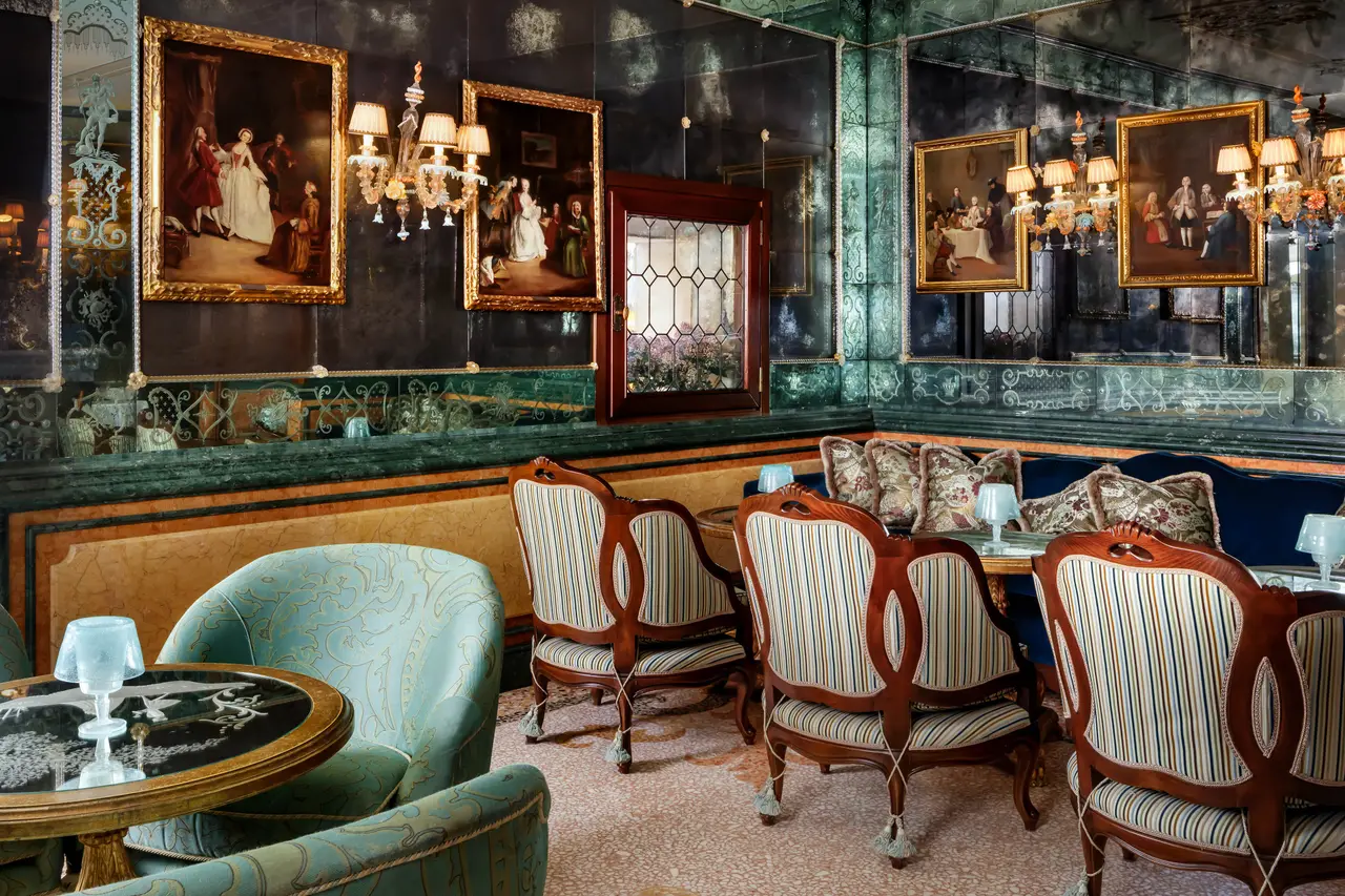 Bar Longhi: striped armchairs around small tables, walls of etched mirror and eighteenth-century paintings in gilt frames.