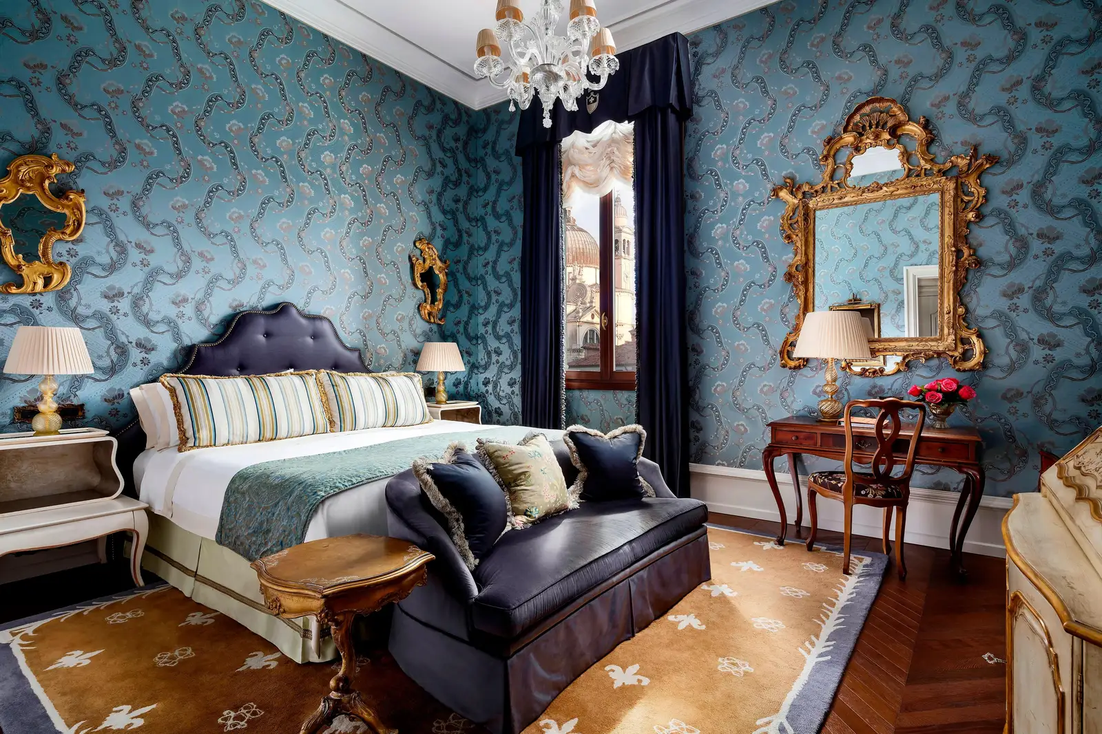 A Landmark Grand Canal room: the king bed, a blue sofa at its foot, gilt mirrors on pale-blue wall fabric and the window onto the canal.