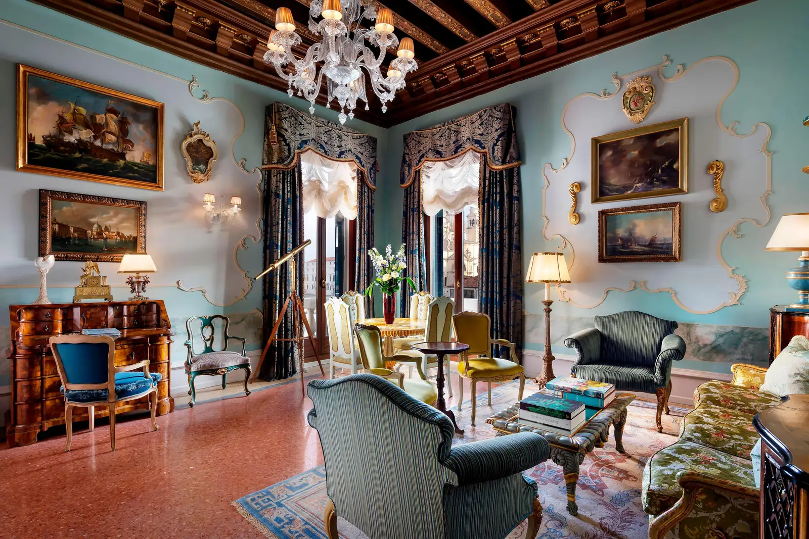 A Patron Suite sitting room: sky-blue walls with stucco and seascapes, a coffered ceiling, a brass telescope and windows onto the Grand Canal.