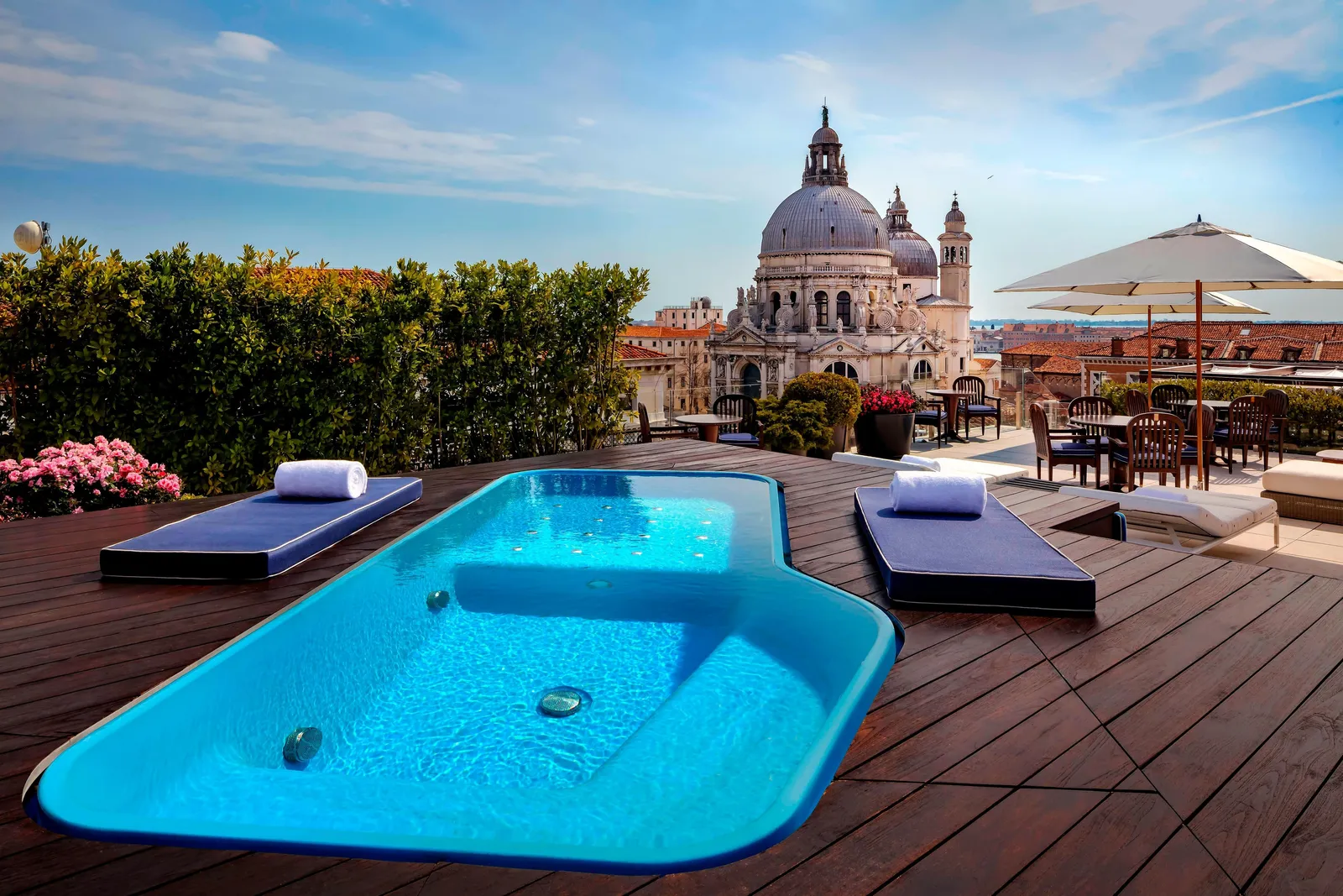The Redentore Suite terrace: the small blue pool set into the wooden deck, 2 loungers and the dome of the Salute above the roofs.