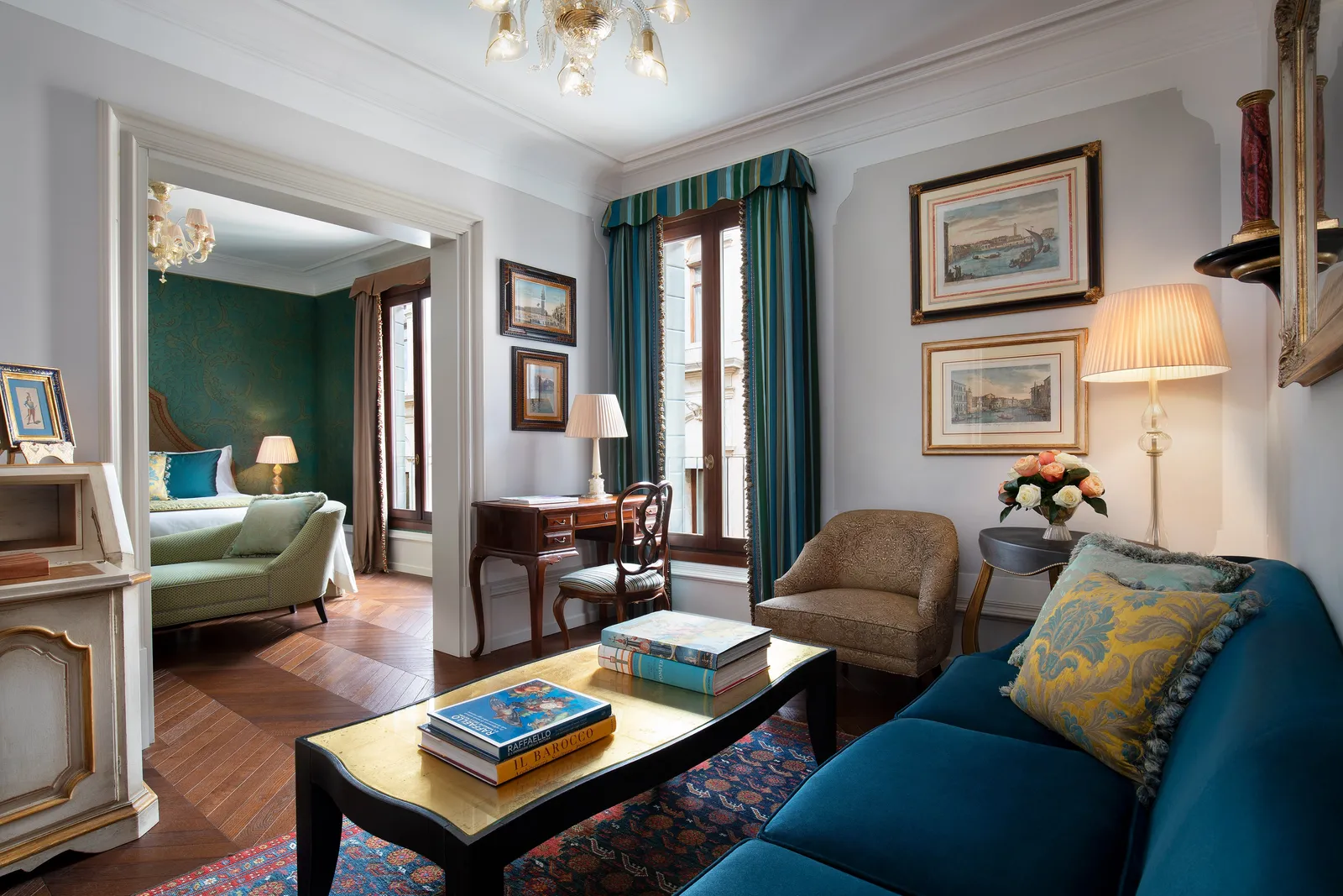 A Sestiere Suite: the sitting room with a blue sofa and gilt coffee table and, through the doorway, the green-walled bedroom.