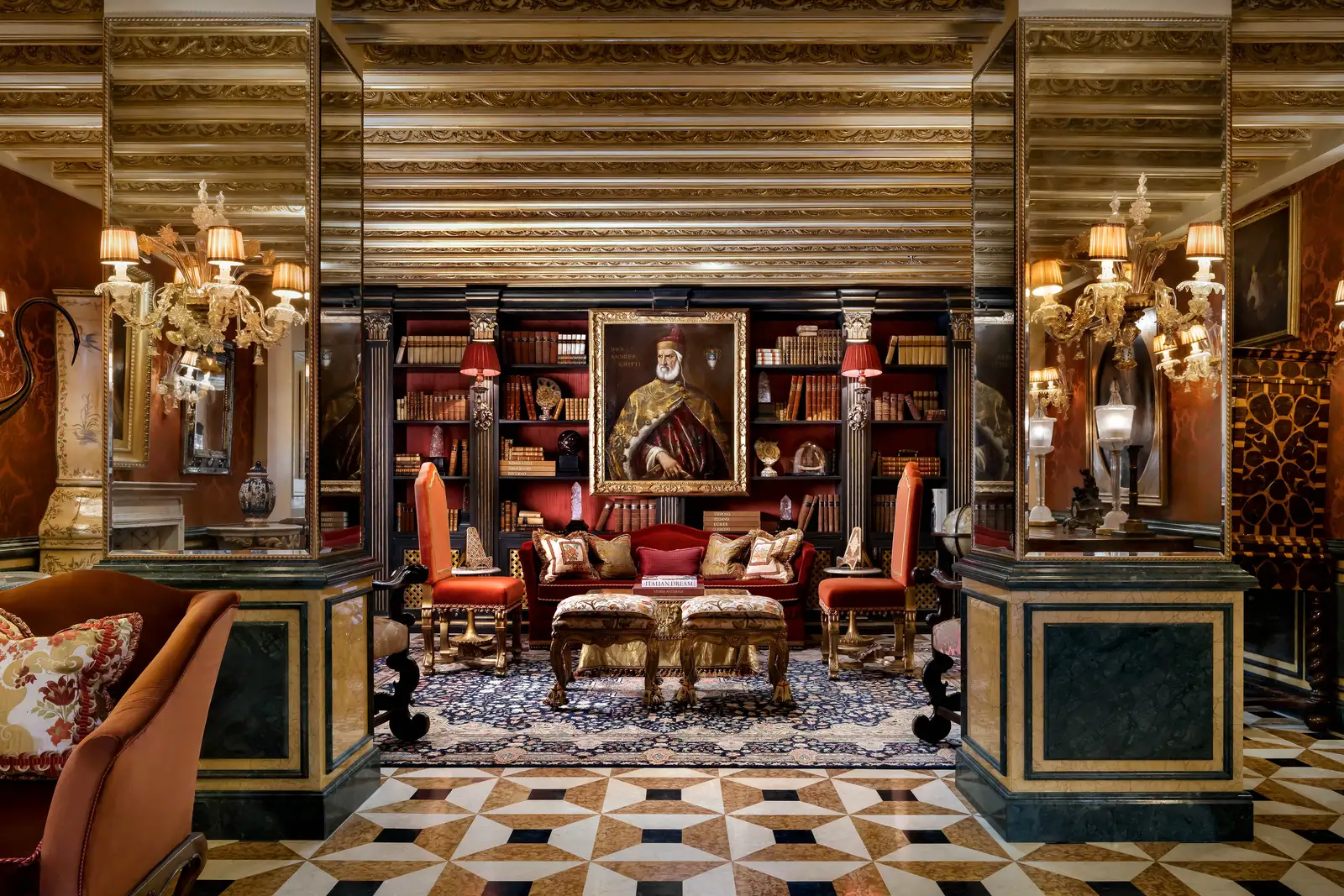 The Explorer’s Library: red sofas before the bookshelves and a doge’s portrait, a gilded beamed ceiling and an inlaid marble floor.