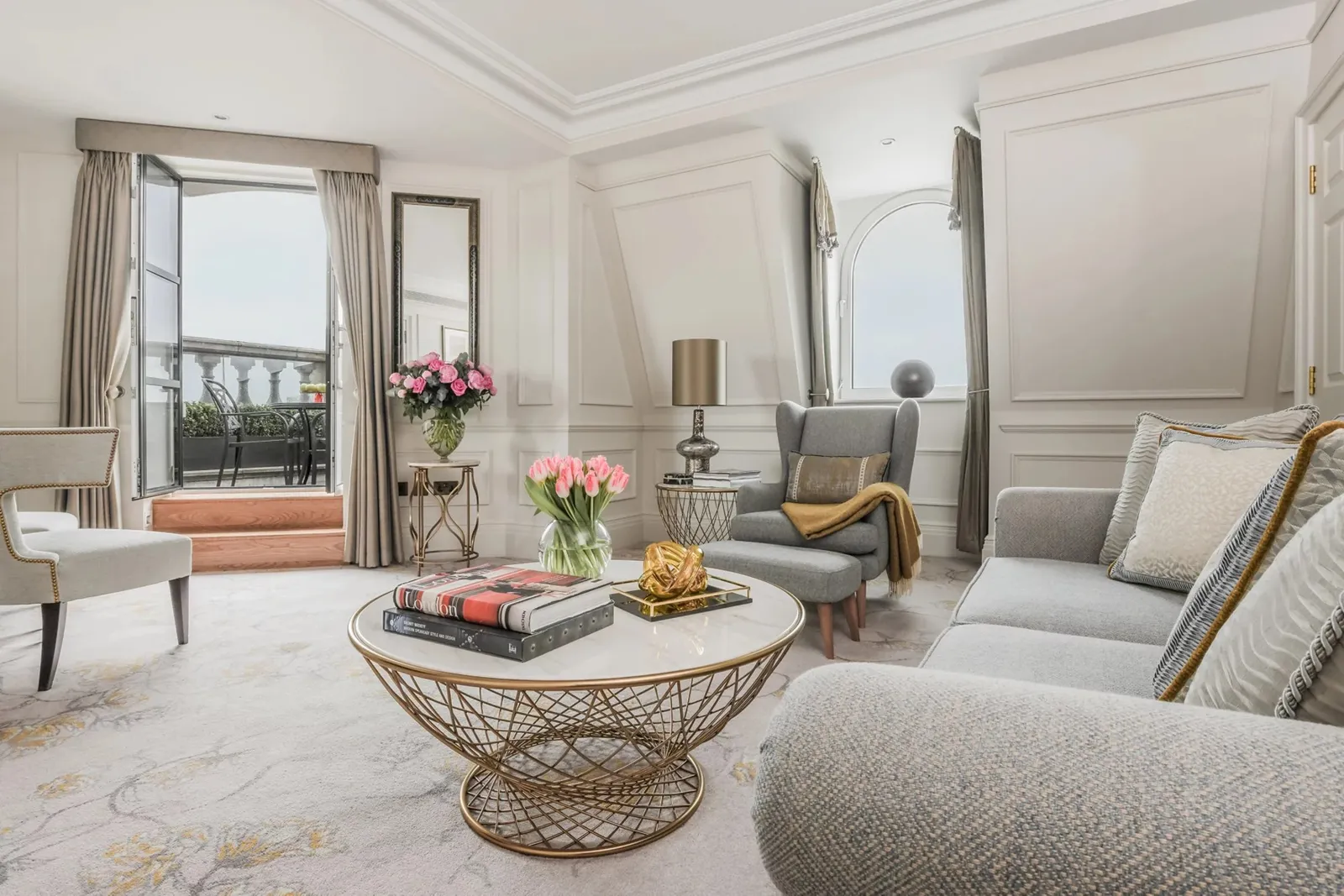 The Cavendish Suite’s sitting room: grey sofas, a round table and a French window onto the terrace