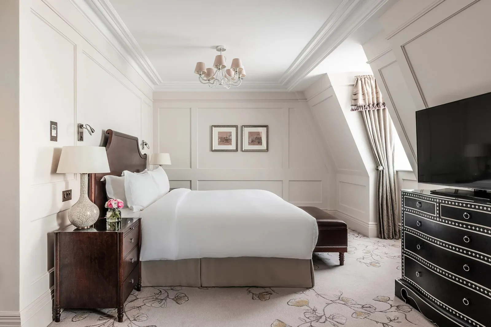 A Club Junior Suite: a king bed under a sloping ceiling, an inlaid chest and a television