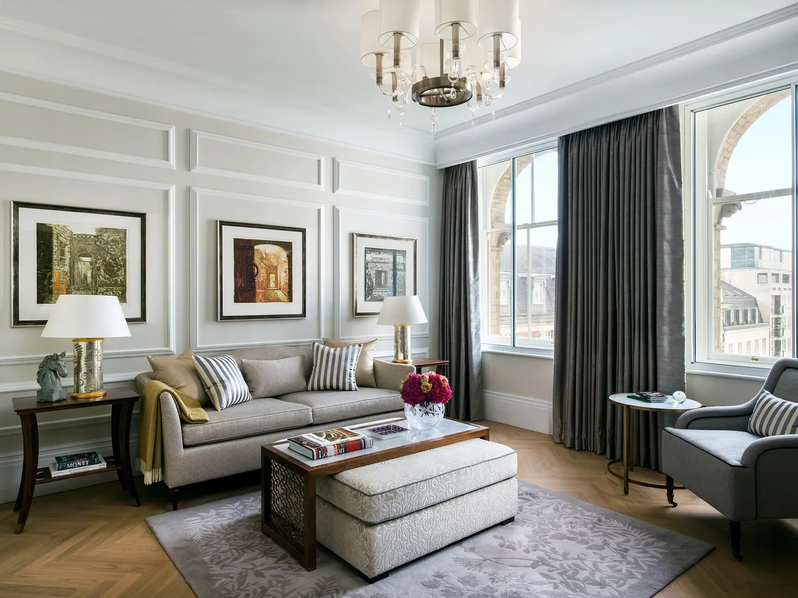 The sitting room of a Club One Bedroom Suite: a sofa, framed pictures and arched windows over the city