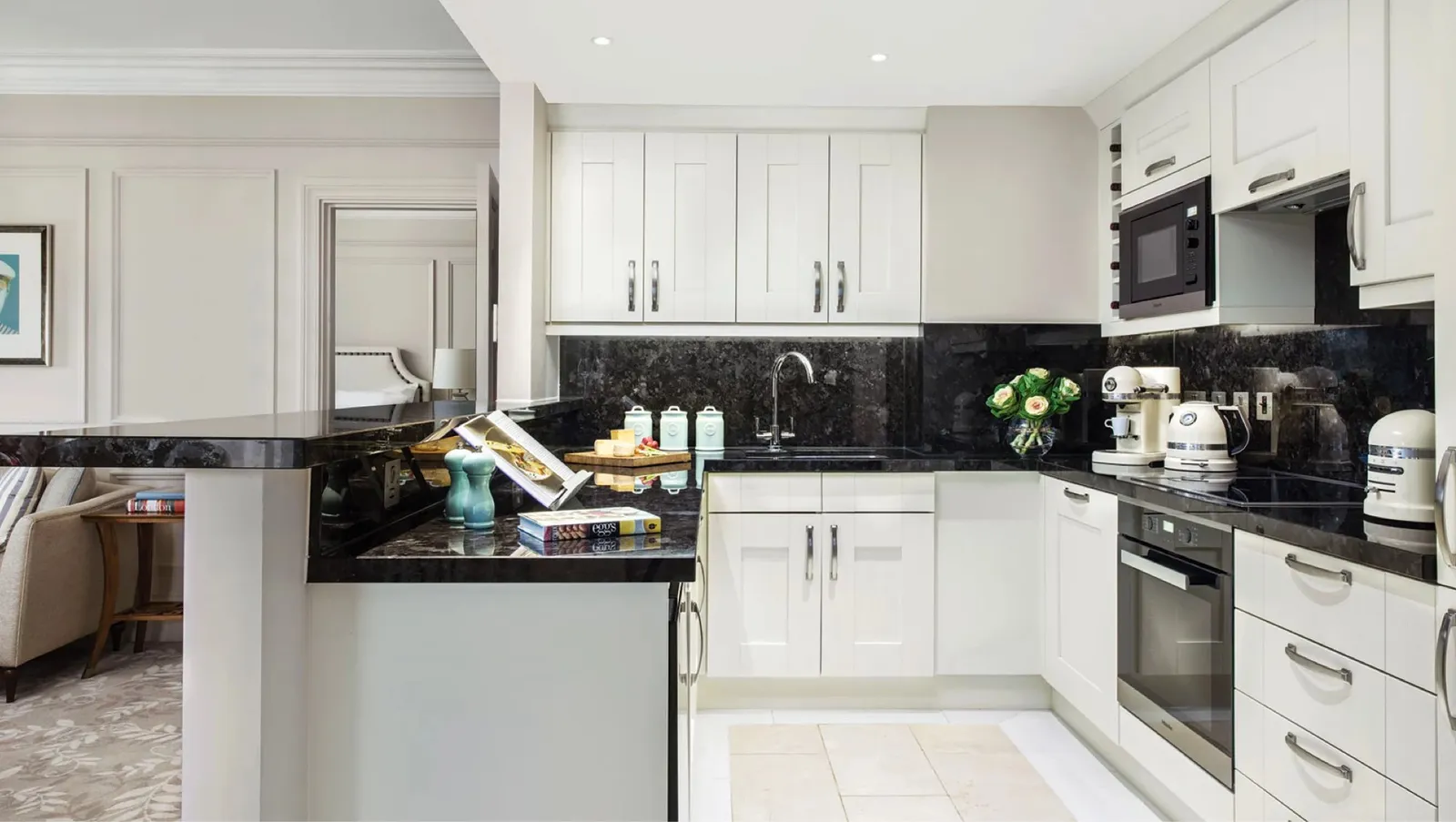 The kitchen of a Club Residence Suite: a black granite worktop, white units, an oven and a microwave