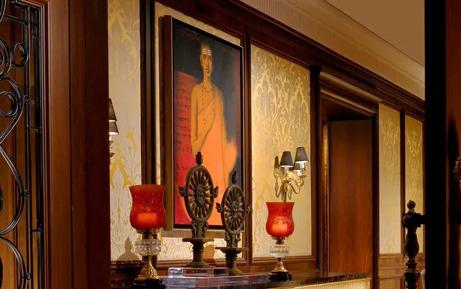 Un dipinto e lampade rosse lungo la galleria d’arte del Leela Palace