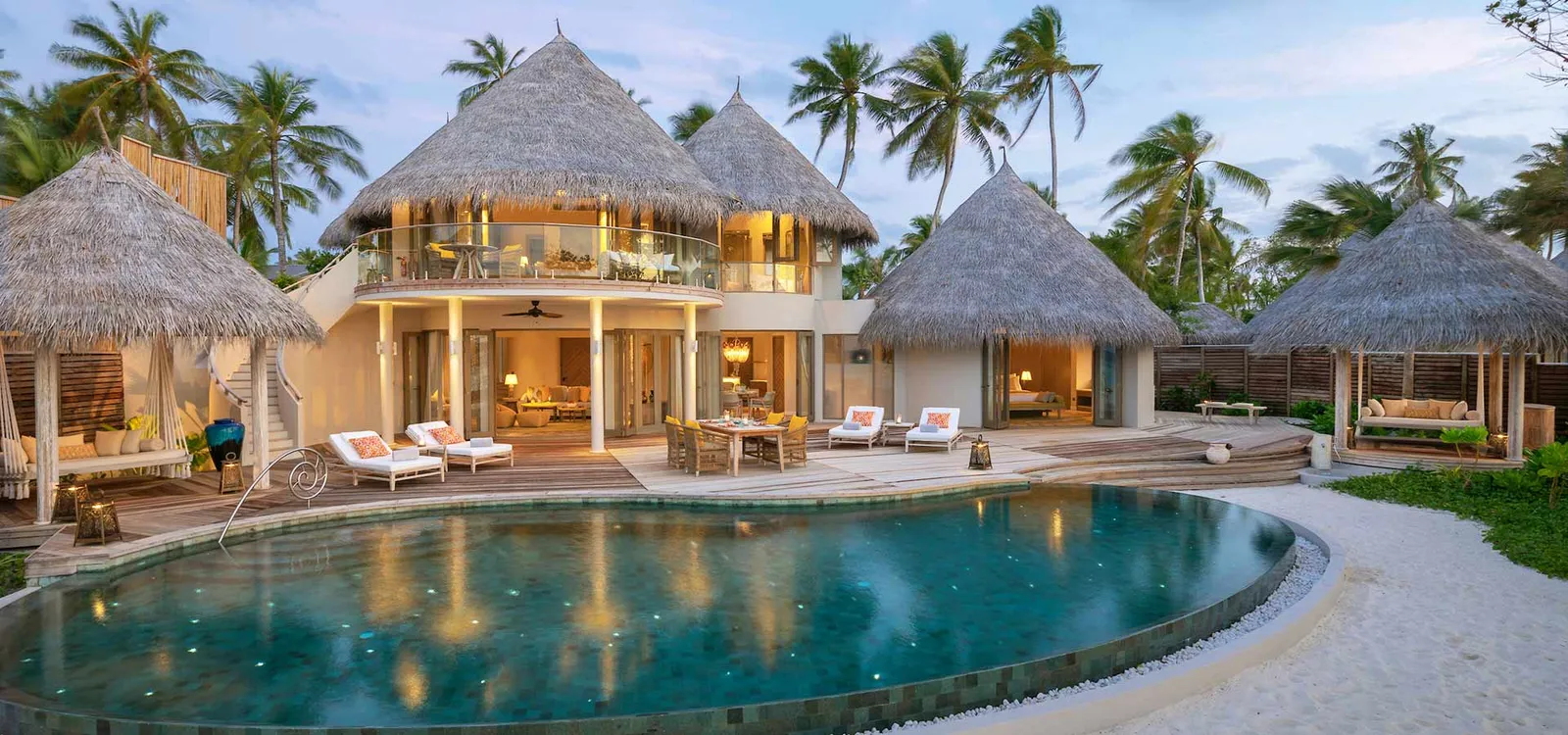 The residence and illuminated pool at dusk.