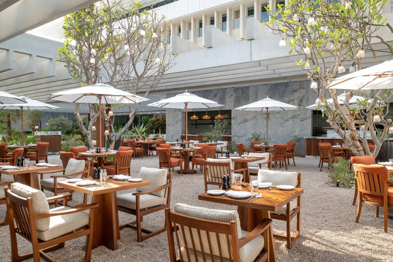 Hadika’s garden, tables under trees and white parasols