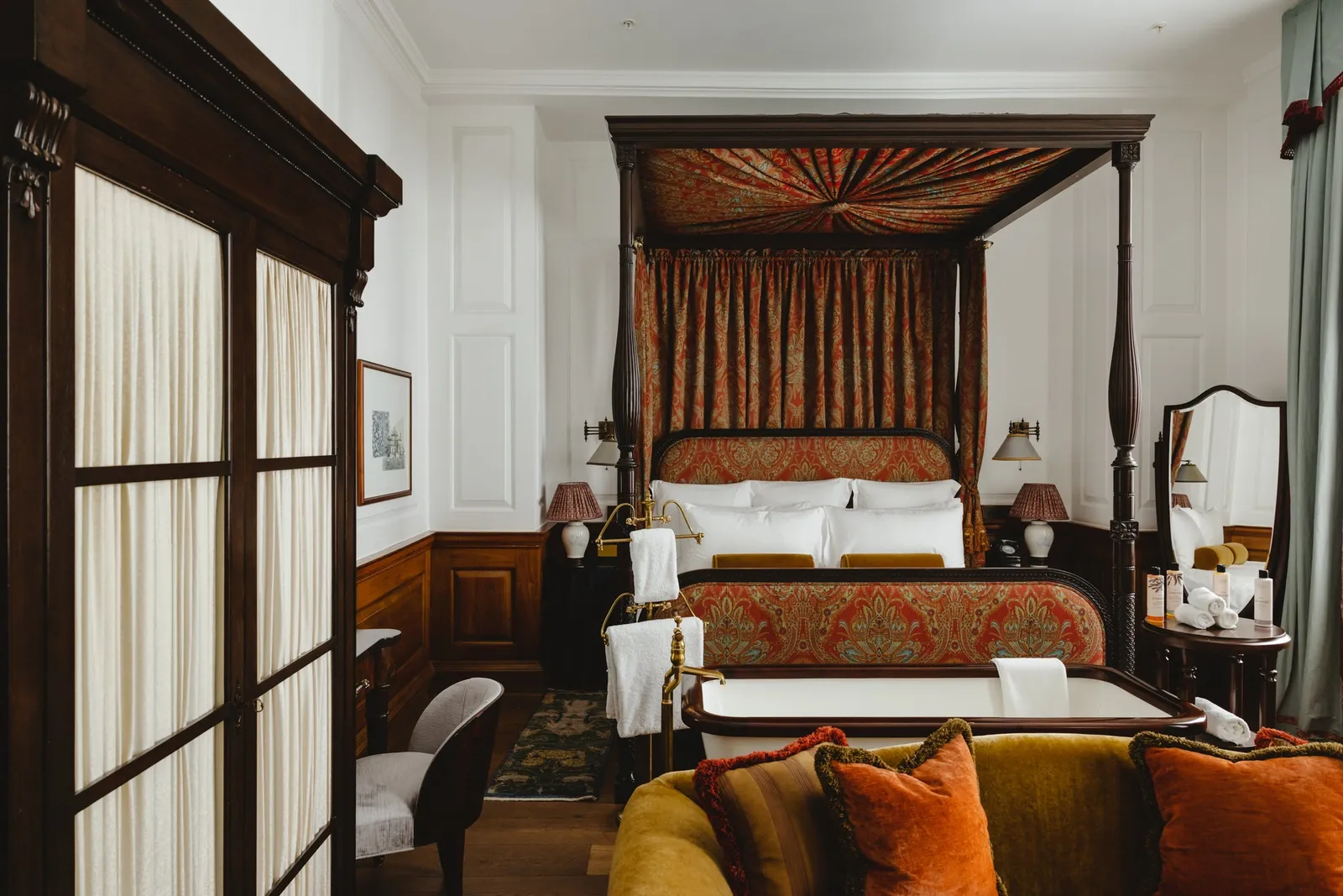 A Heritage room: a canopy bed, walnut-panelled walls and an orange sofa